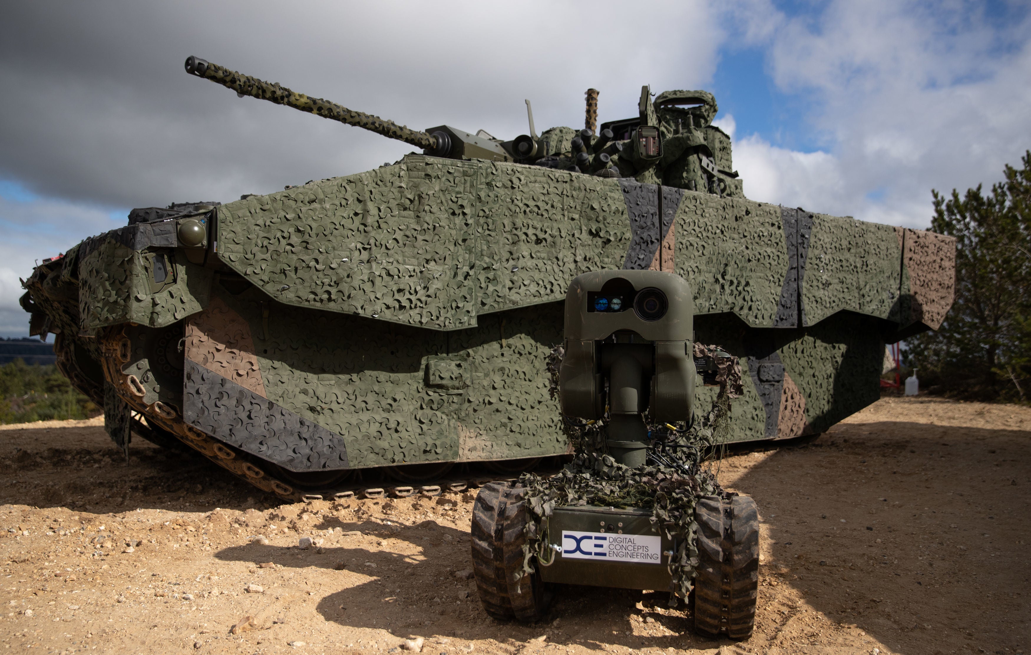 General Dynamics developed Ajax armoured fighting vehicle behind an all-terrain unmanned ground vehicle at Bovington Camp in Dorset – file photo