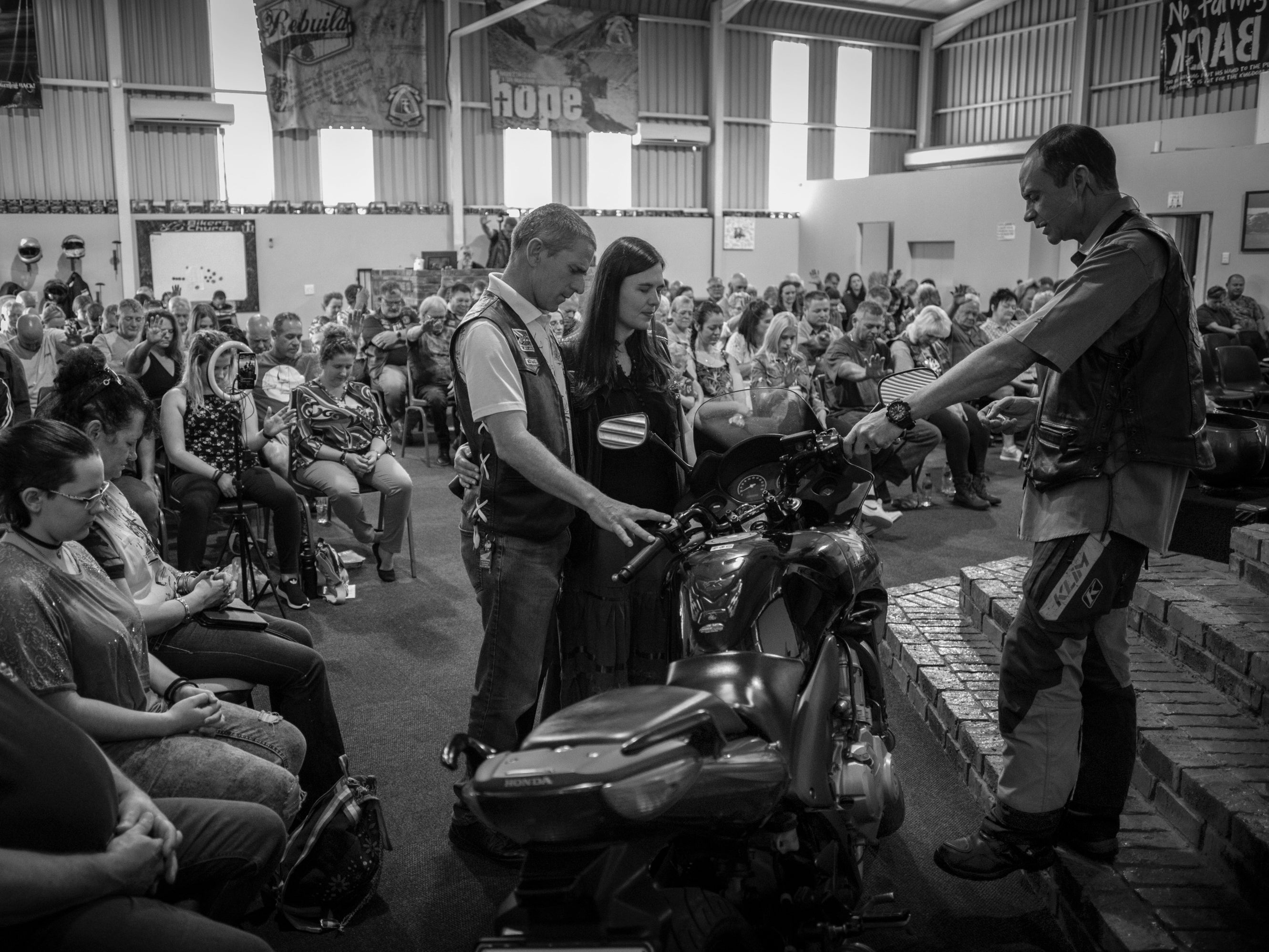 Pastor Mozzy Delpeche (right) leads a prayer for a couple who had recently purchased a new motorcycle at a weekly CMA service in Johannesburg