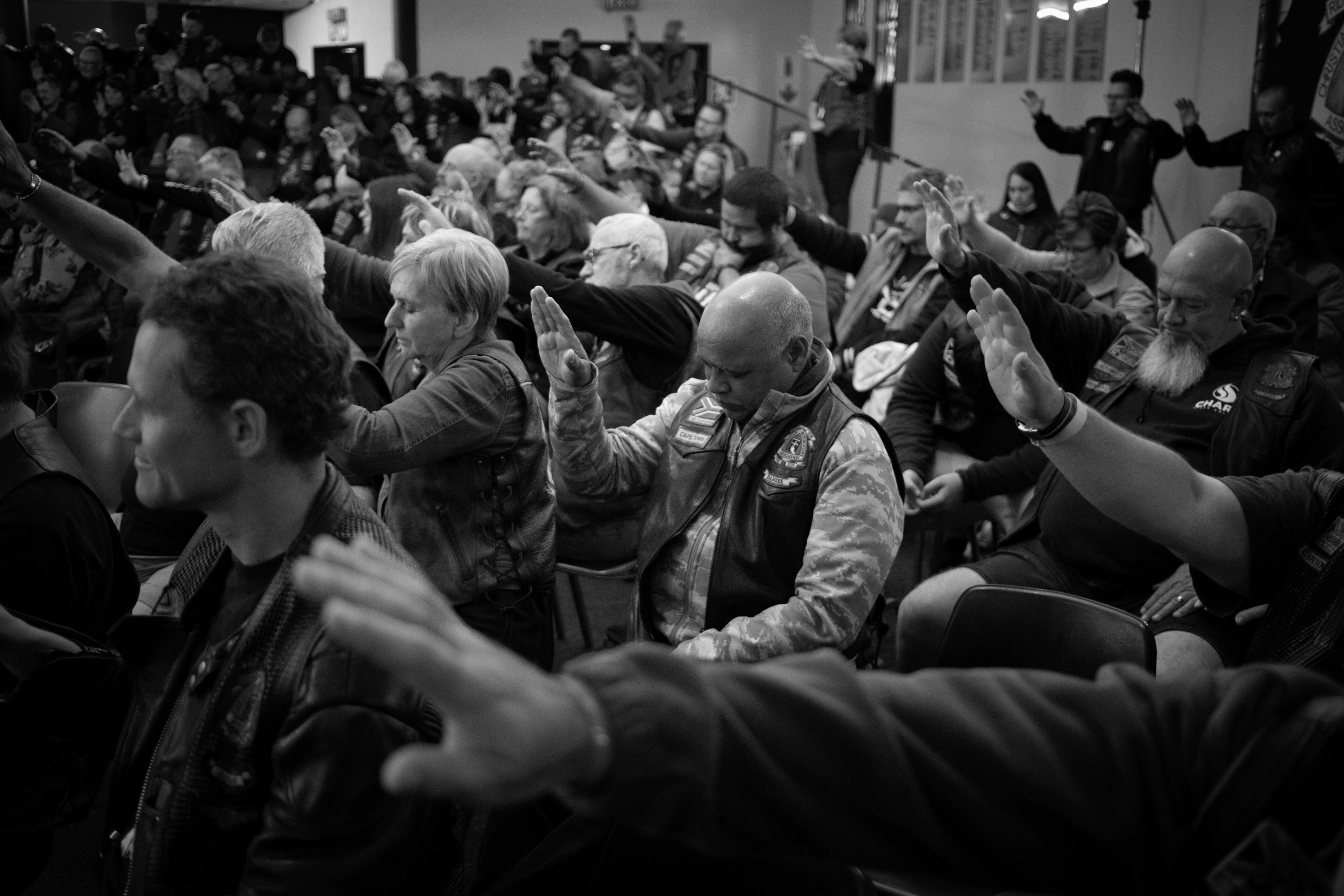 People raise their hands as they pray