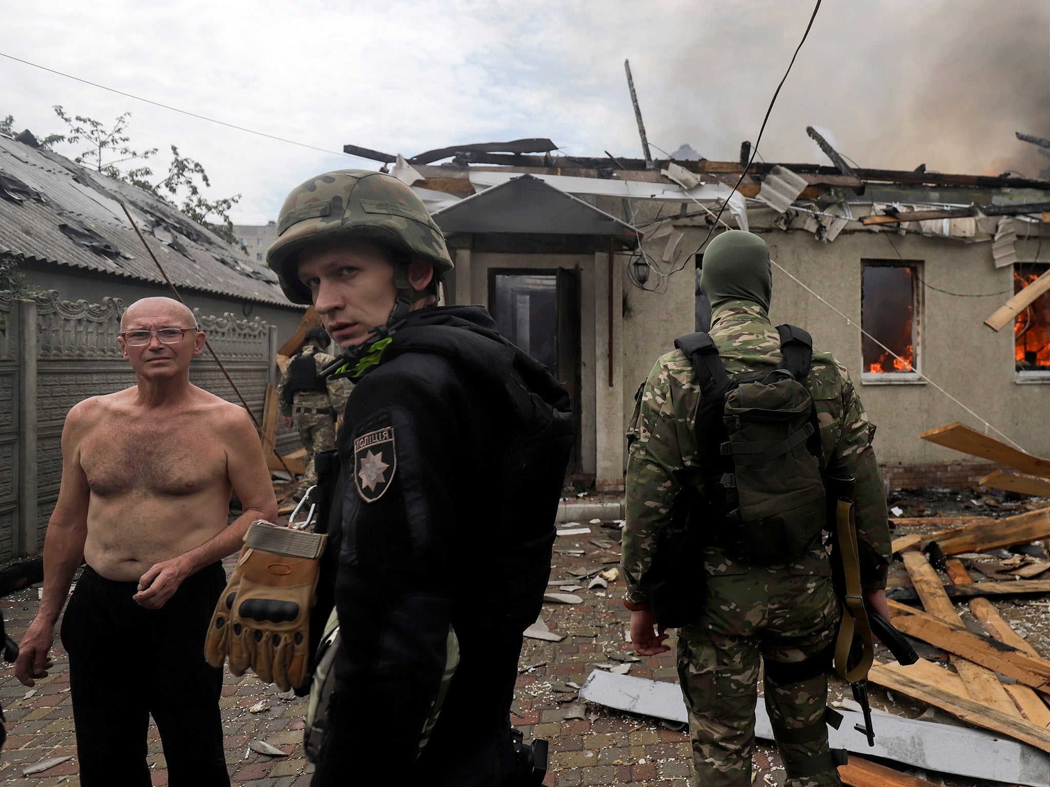 Ukrainian troops speak with a local man near a damaged private building in Lysychansk