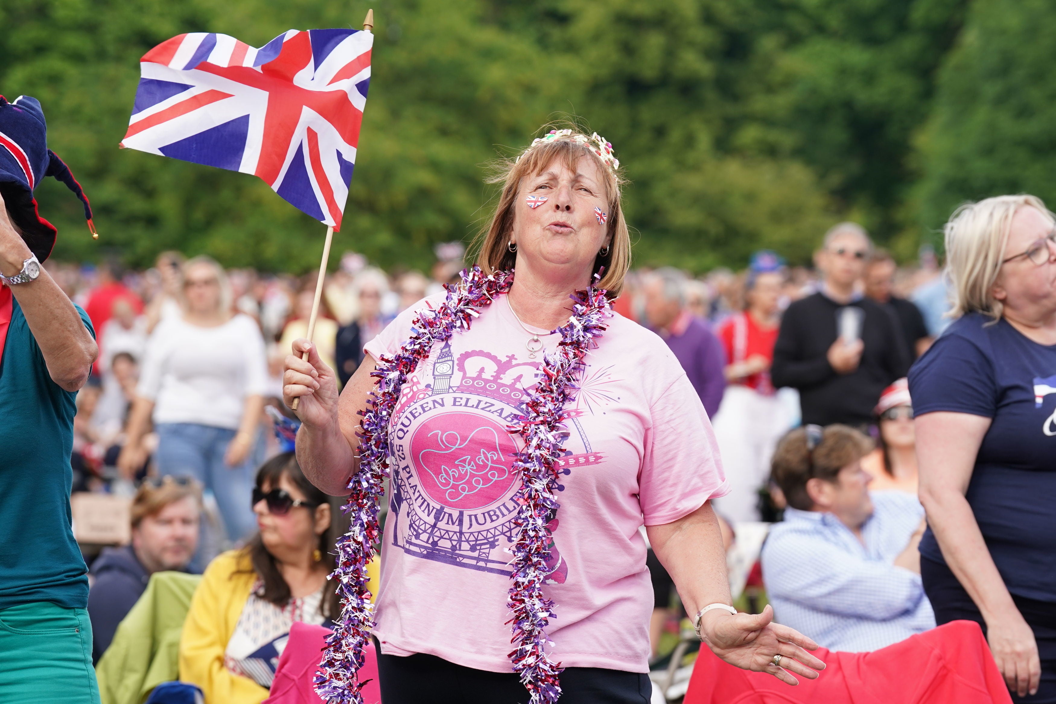 A lady watches a screen in St James's Park before the start of the Platinum Party at the Palace in front of Buckingham Palace