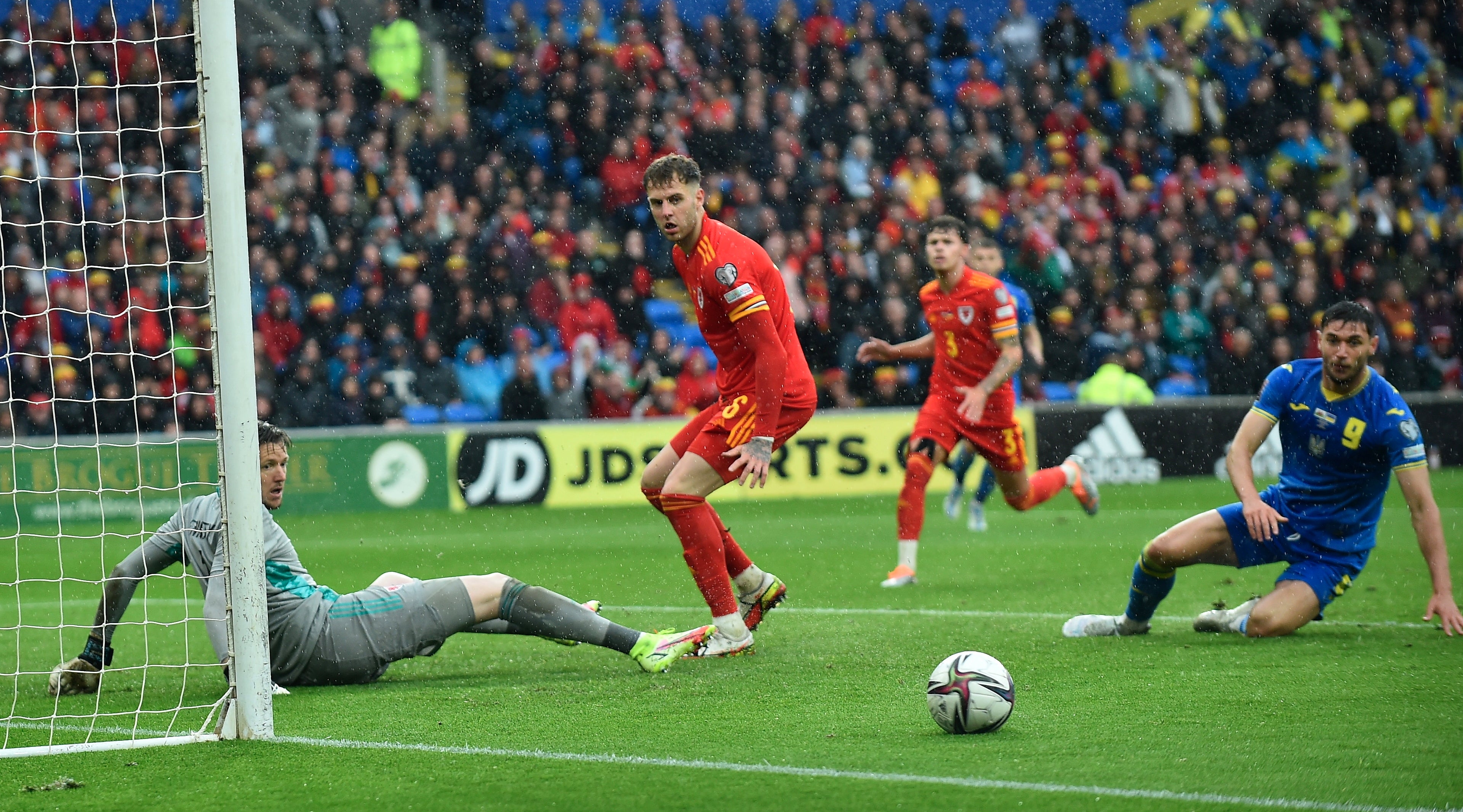 Wales defenders watch as the ball runs wide