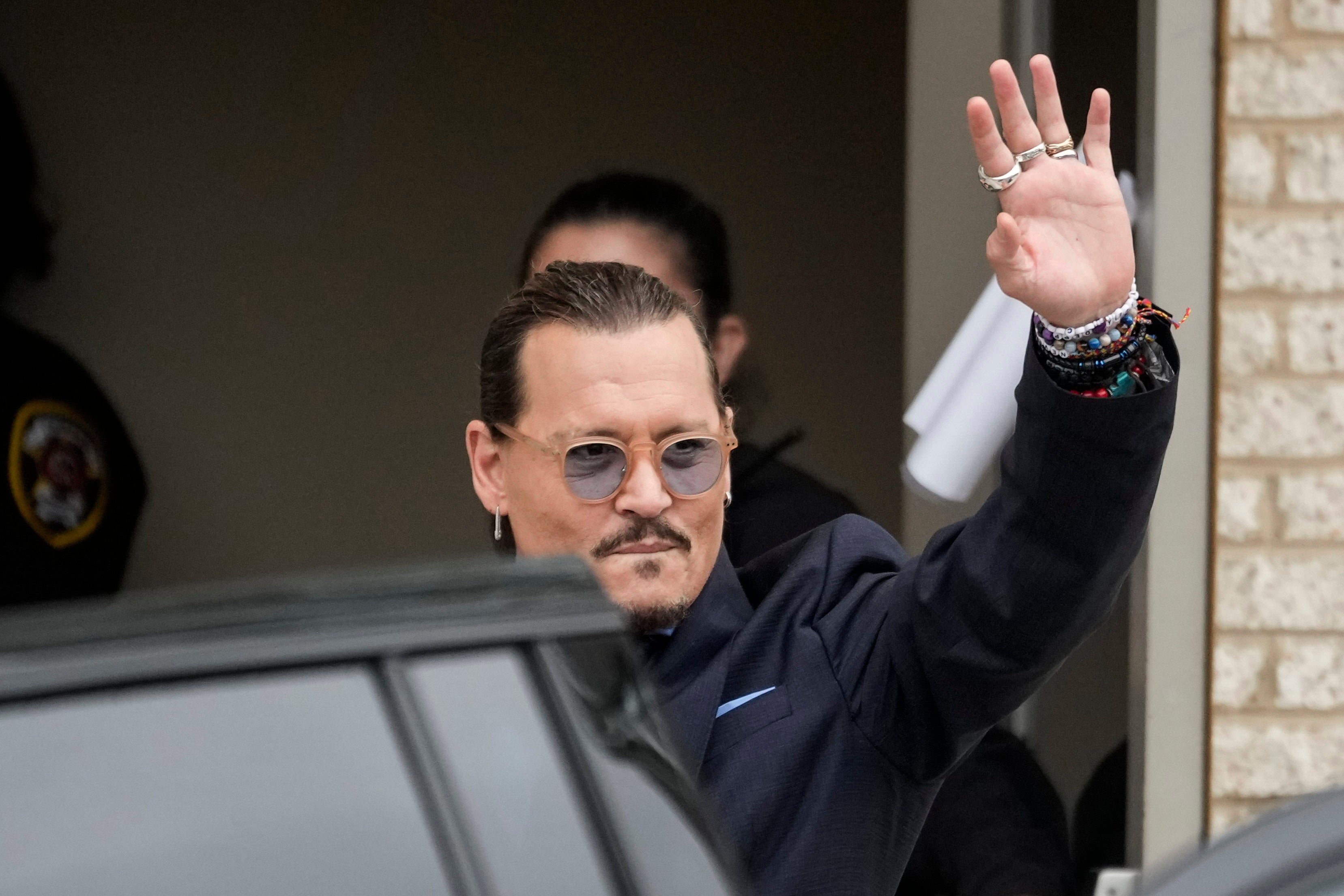 Johnny Depp waves to fans outside court during the trial