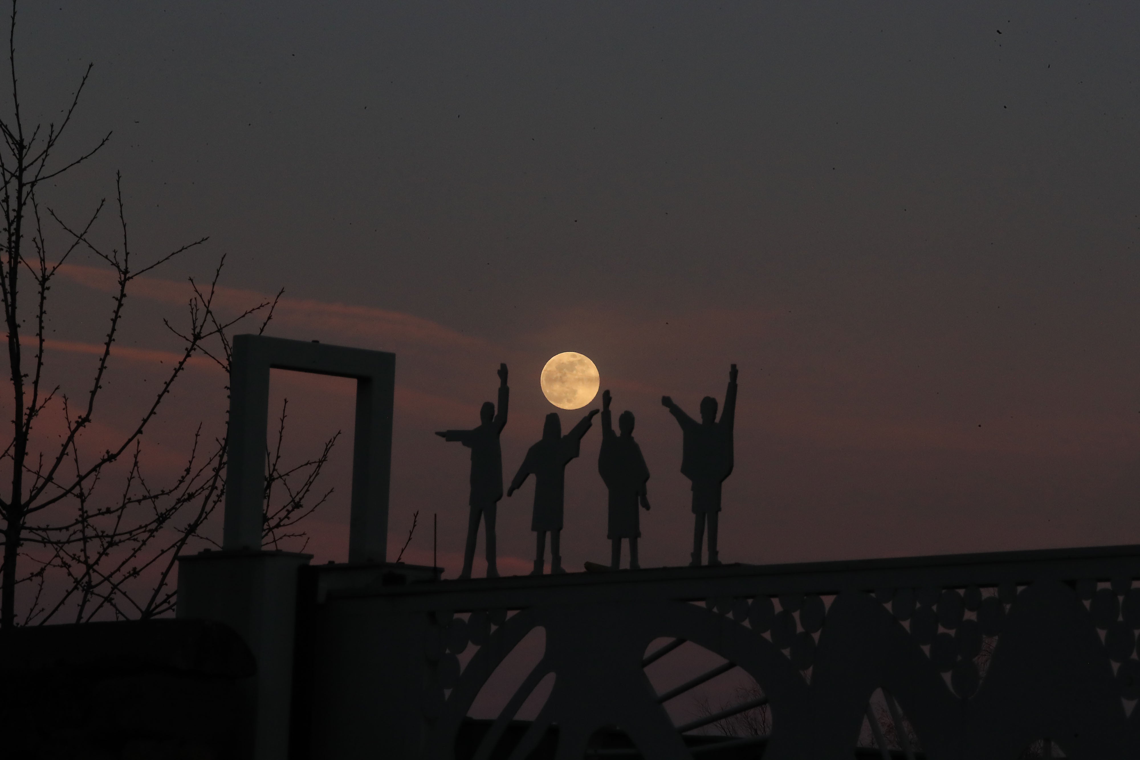 The moon rises behind a statue of the Beatles on Penny Lane in Liverpool (Peter Byrne/PA)