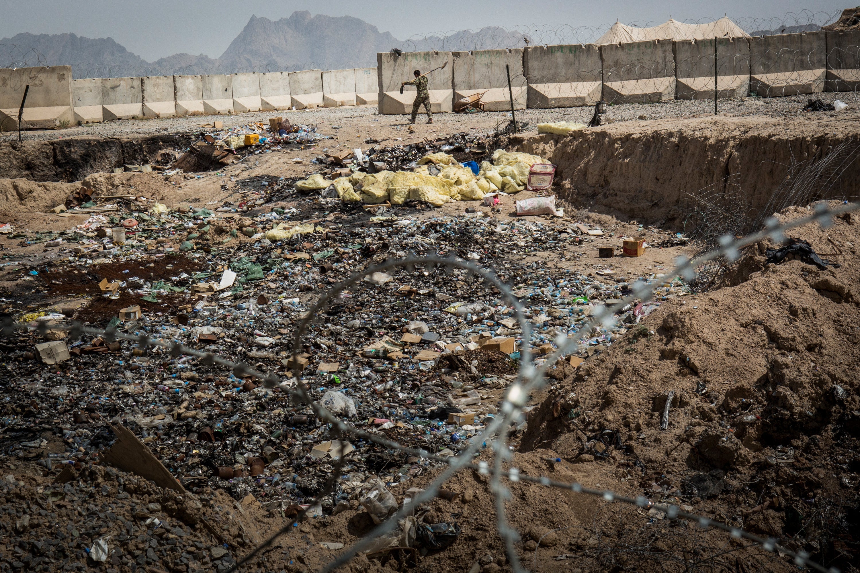 A soldier in the Afghan National Army (ANA) walks past a burn pit at a command outpost recently handed over to the ANA from the United States Army on March 22, 2013 in Kandahar Province, Zhari District, Afghanistan.