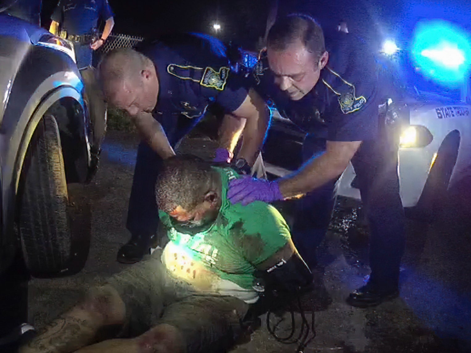 In this image from the body camera of Louisiana State Police Trooper Dakota DeMoss, his colleagues, Kory York, center left, and Chris Hollingsworth, center right, hold up Ronald Greene before paramedics arrived on May 10, 2019, outside of Monroe, La