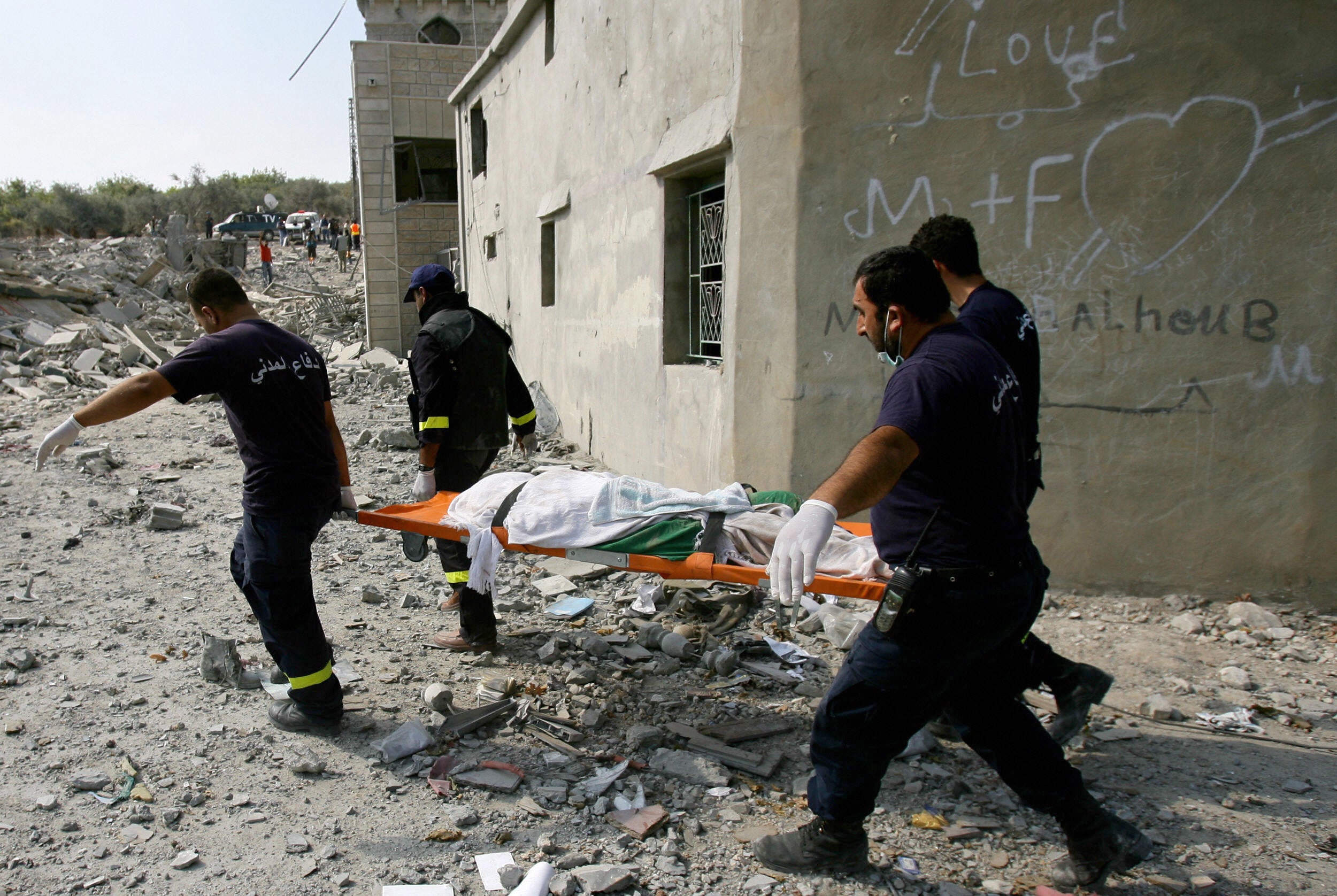 Rescue workers carry a dead body through the rubble after Israeli airstrikes in Qana