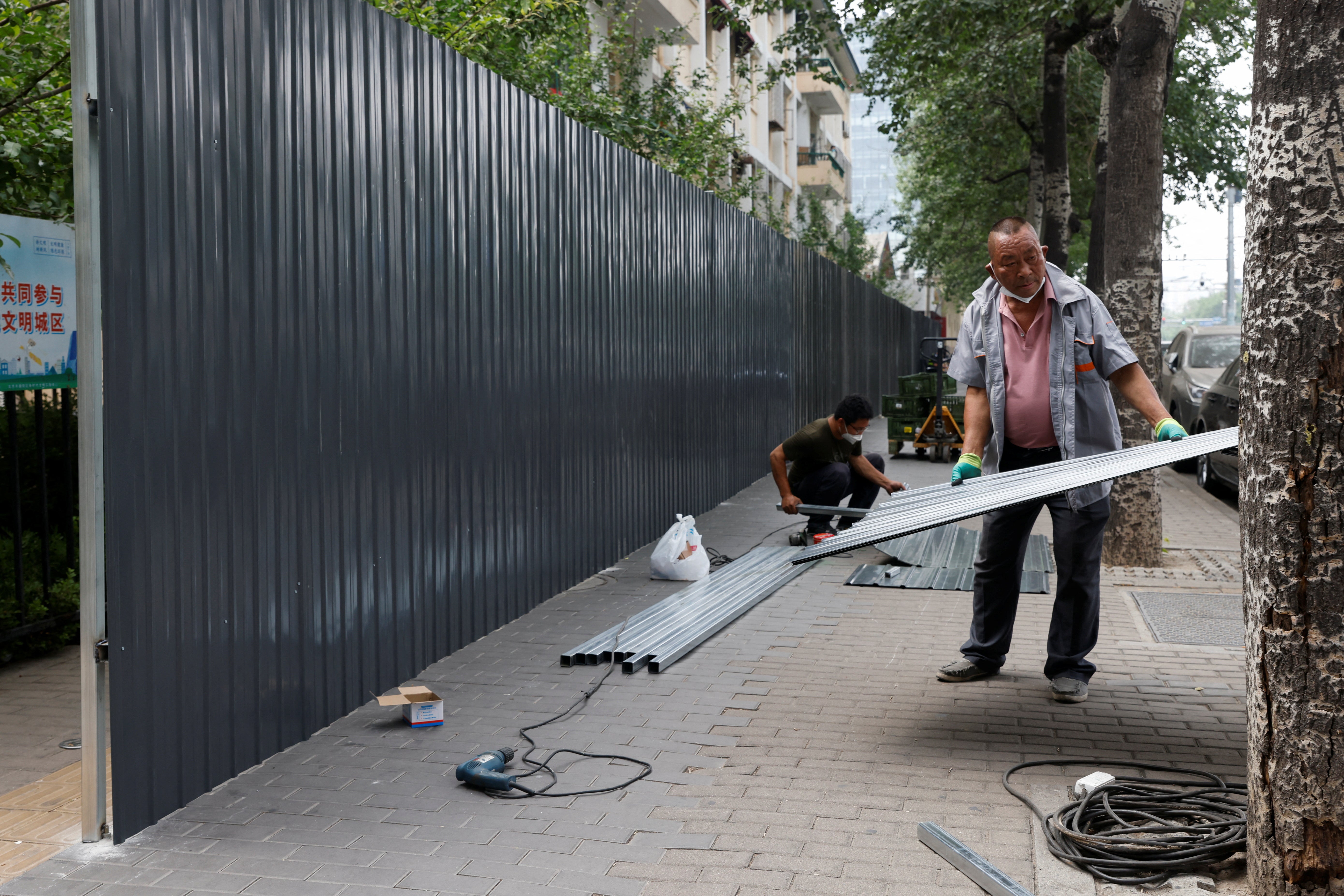 A worker installs a barricade around a residential area under lockdown in Beijing