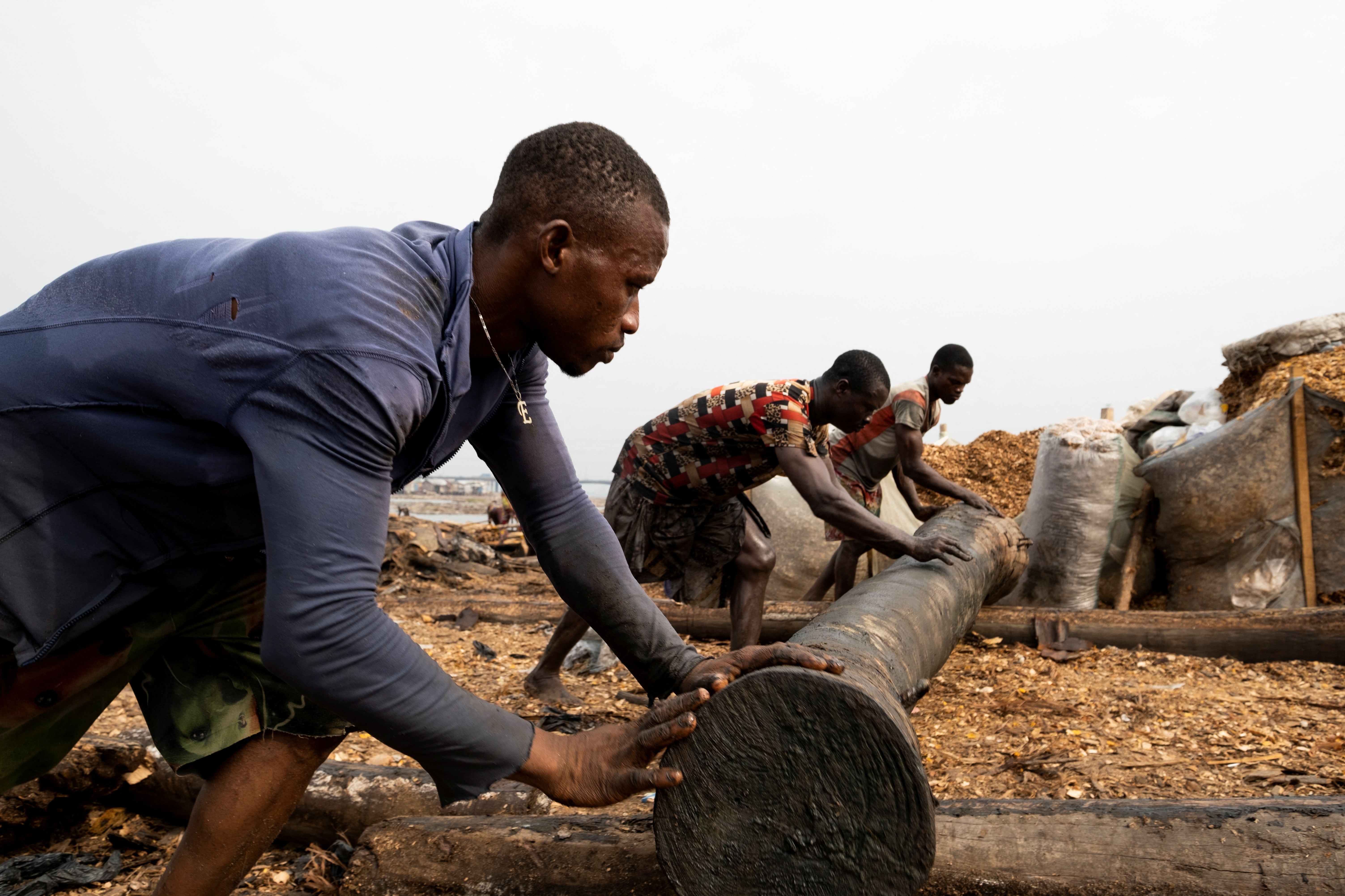 Sawmill workers roll a log out of the Lagos lagoon at the Ebute Metta sawmill in Lagos