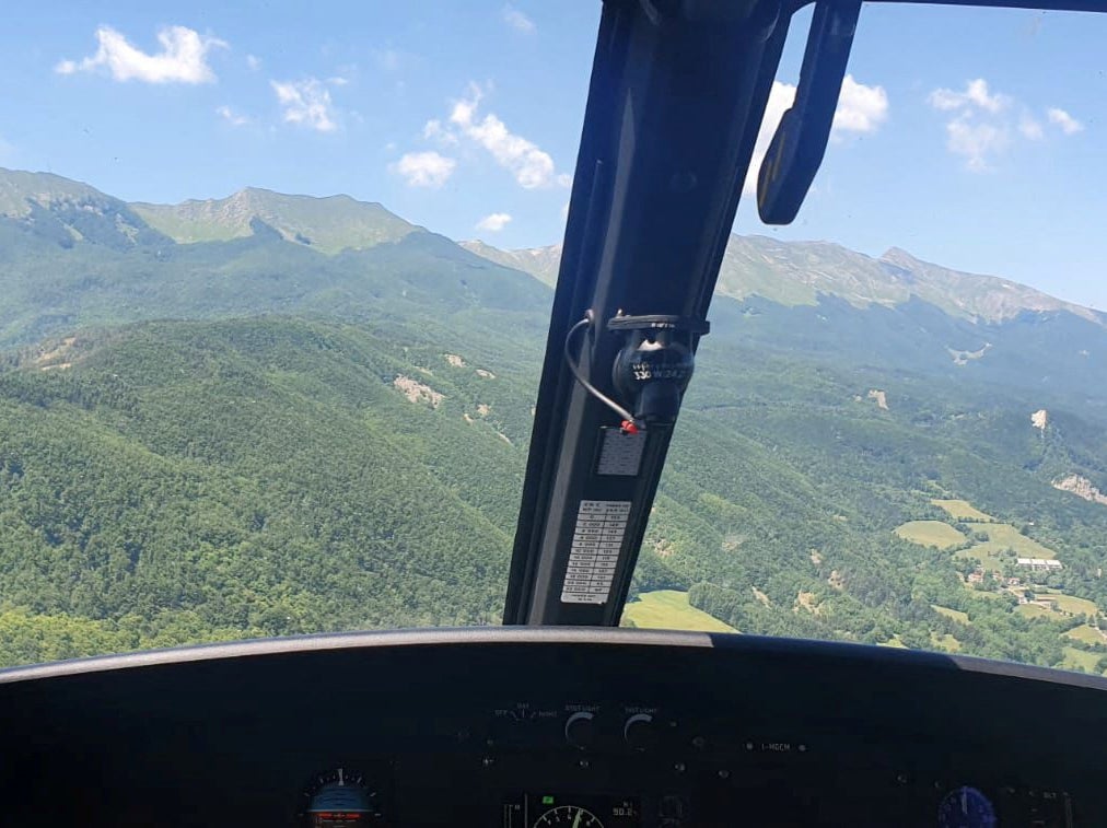 An Alpine Rescue helicopter flies over the crash site in Tuscany