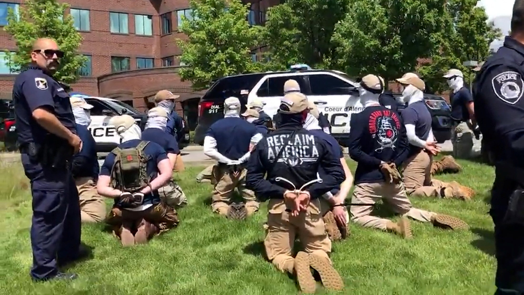 Police officers guard a group of men, who police say are among 31 arrested for conspiracy to riot and are affiliated with white nationalist group Patriot Front, after they were found in the rear of a U Haul van in the vicinity of a North Idaho Pride Alliance LGBT+ event in Coeur d’Alene, Idaho