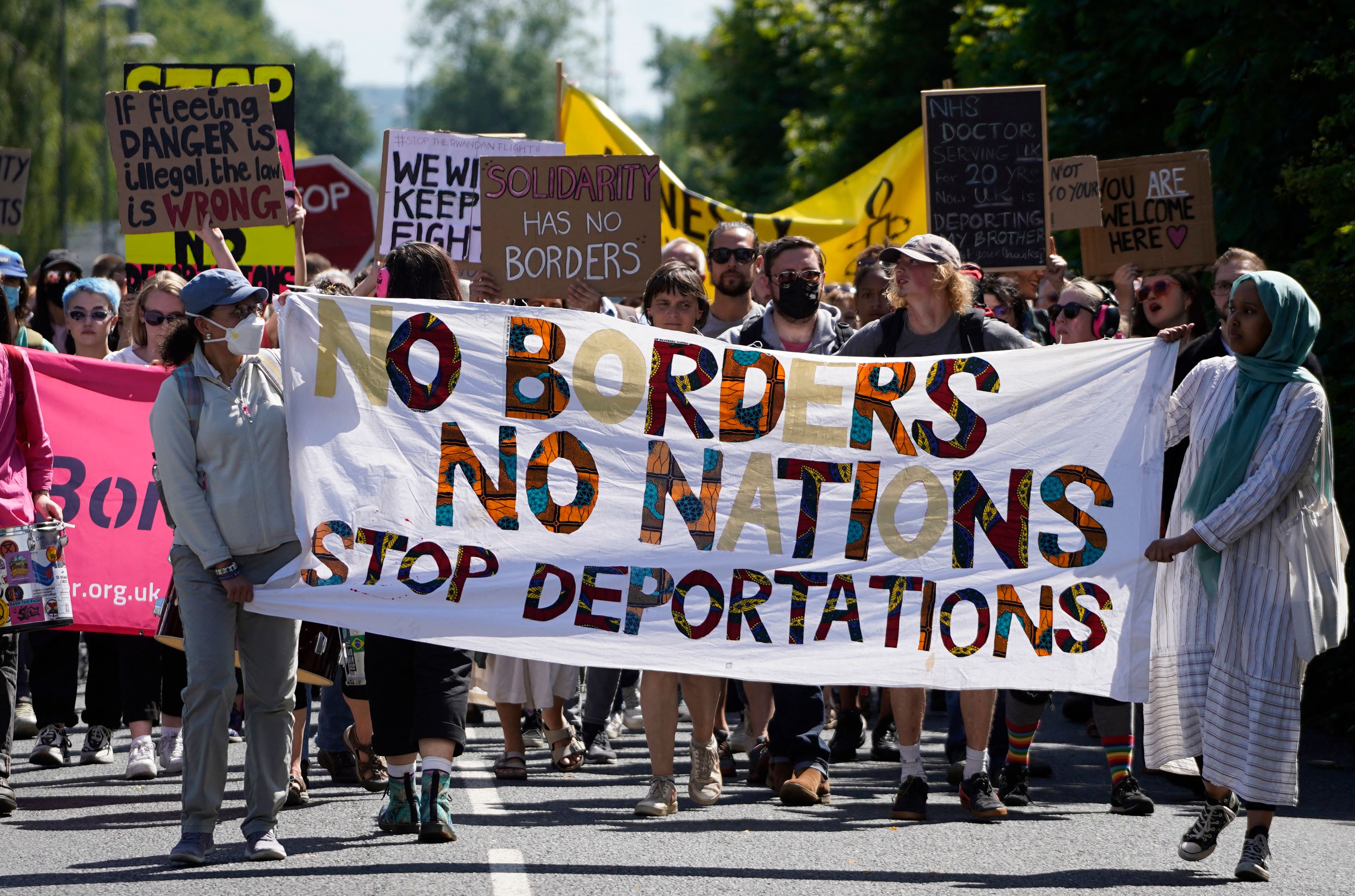 Protesters hold up placards as they march towards the Brook House