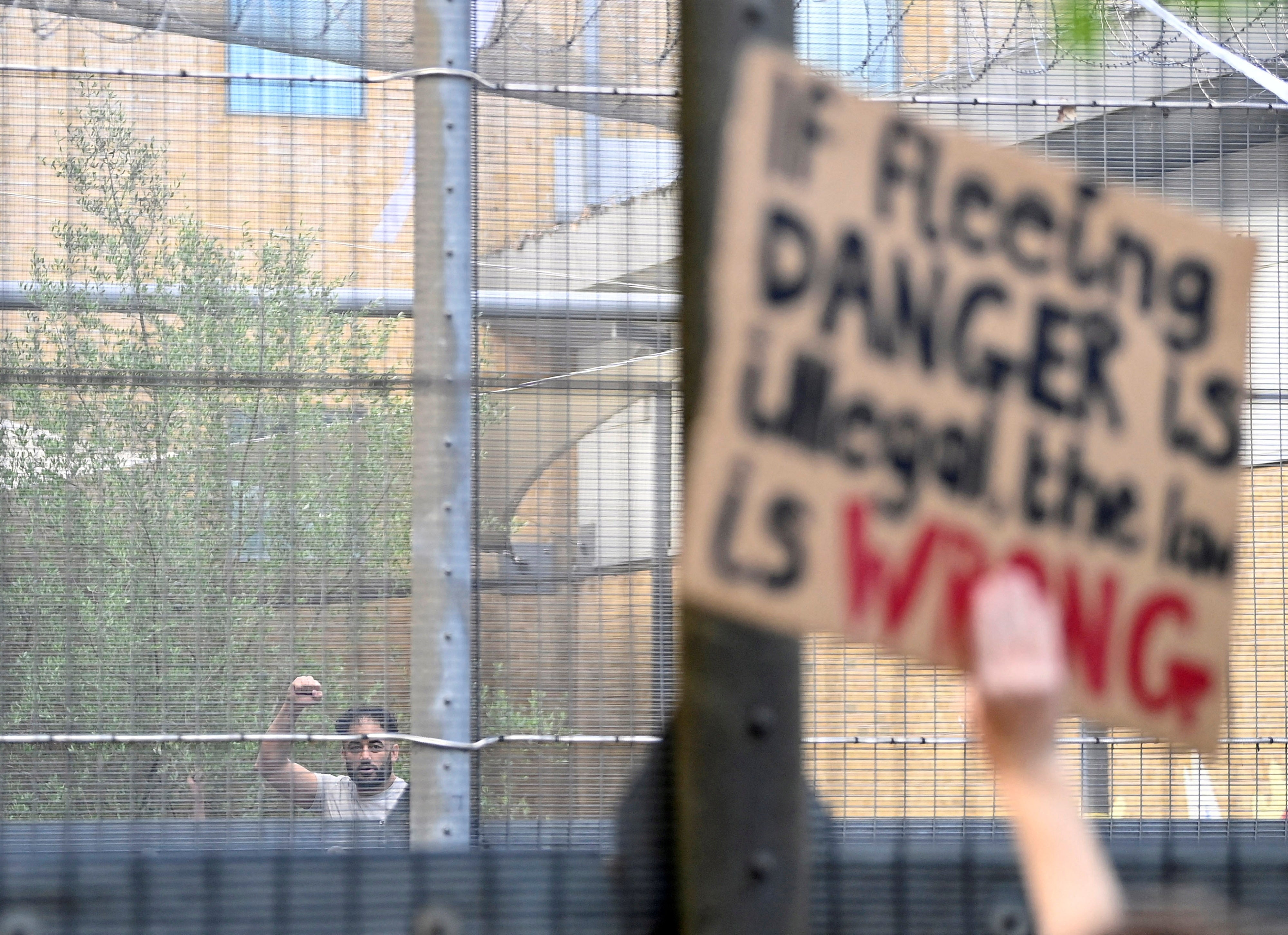 A detainee gestures as demonstrators protest outside of it against a planned deportation of asylum seekers from Britain to Rwanda