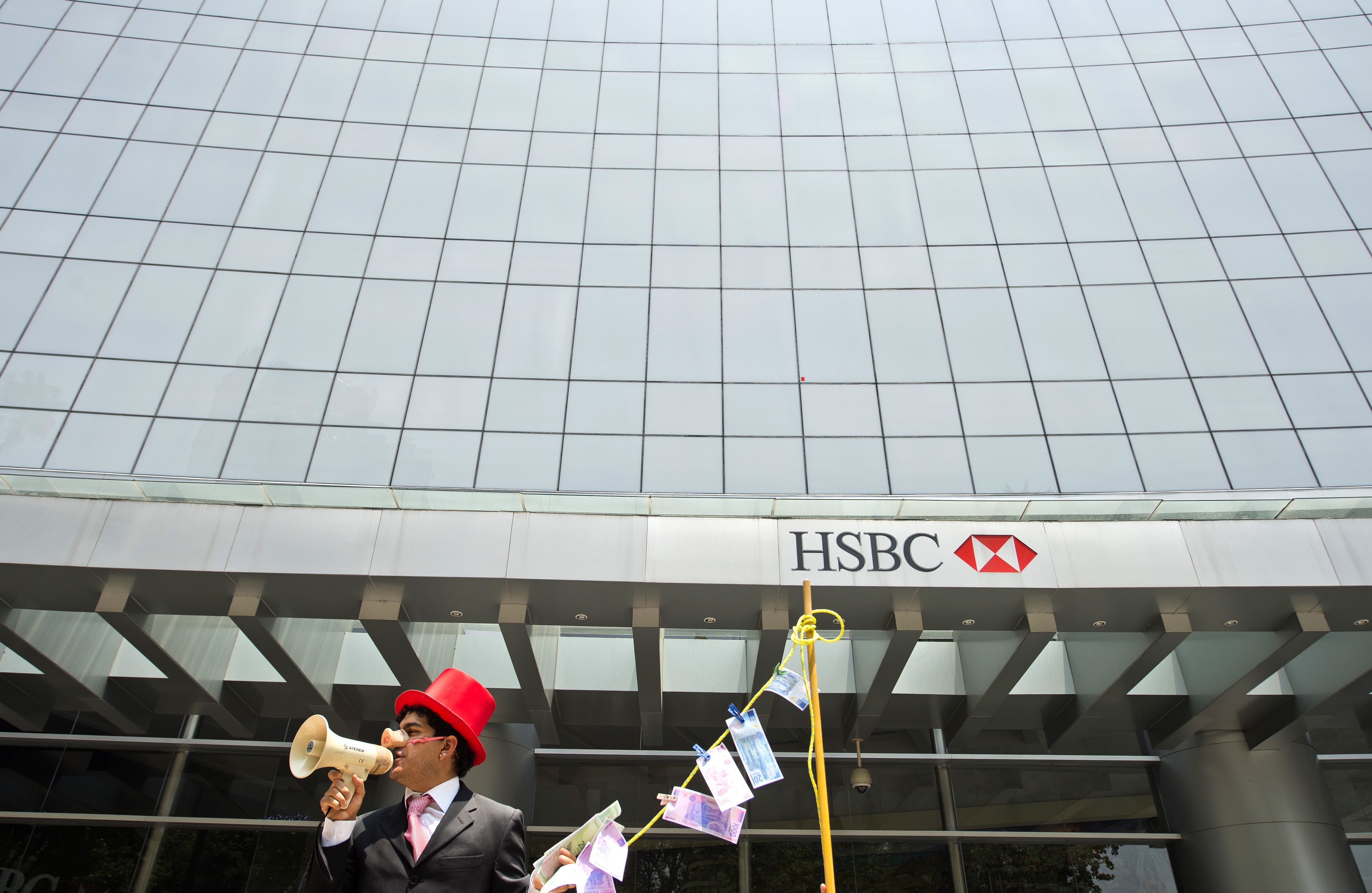 A man wearing a pig nose and holding fake, laundered banknotes during a protest in front of a HSBC branch building in Mexico City