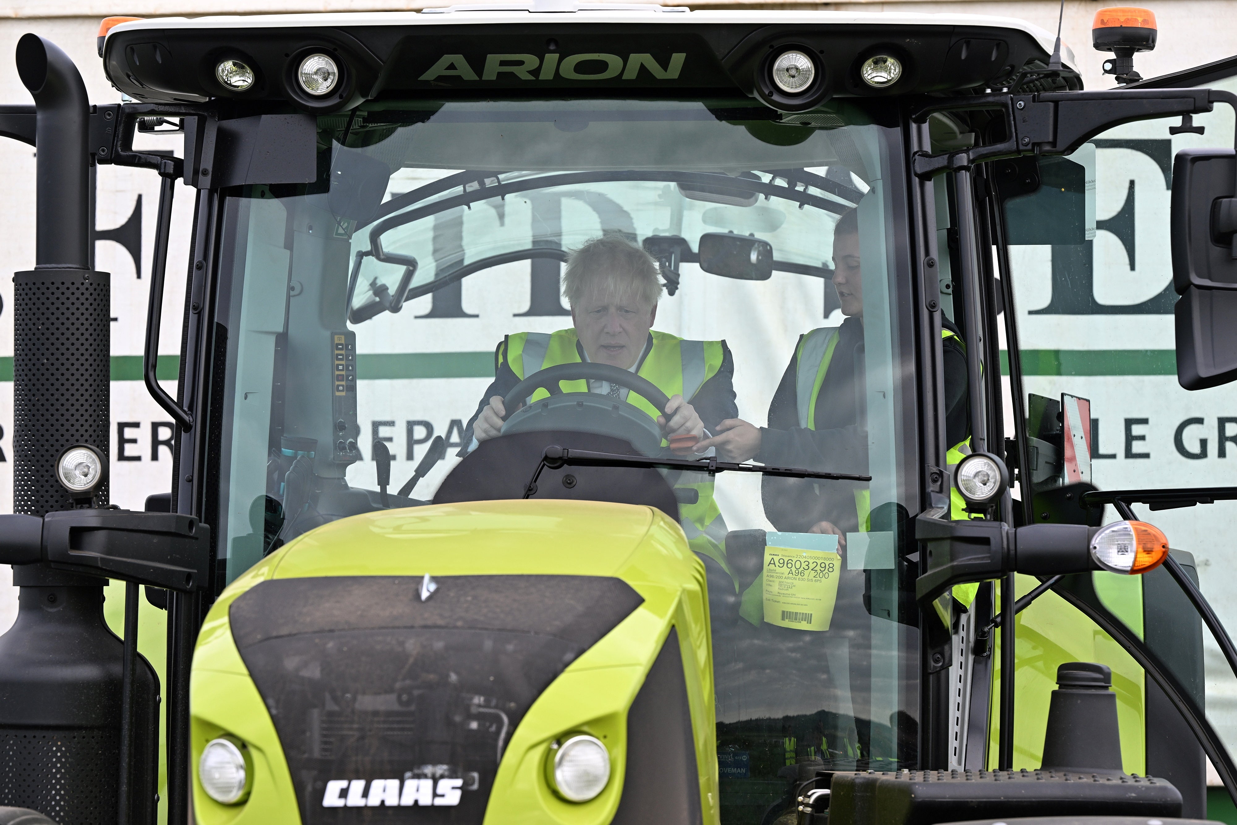 Prime Minister Boris Johnson is instructed as he drives a tractor during a visit to Southern England Farms Ltd in Hayle, Cornwall