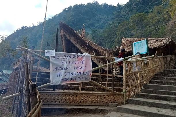 A man walks behind a placard posted at the venue of the Hornbill festival, which was shut after Indian security forces killed civilians in December 2021