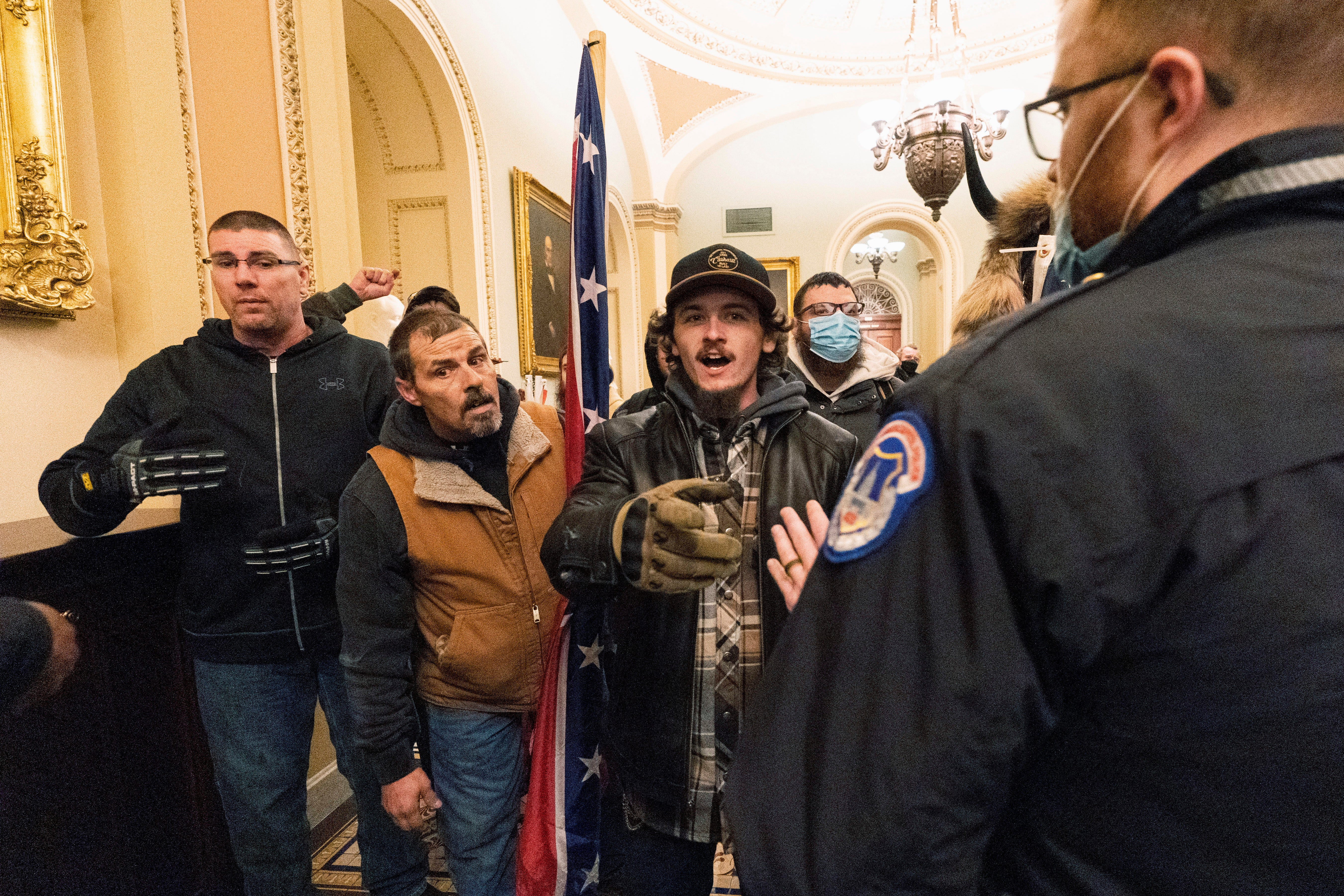 Kevin Seefried, second from left, holds a Confederate battle flag during a riot at the US Capitol on 6 January, 2021.