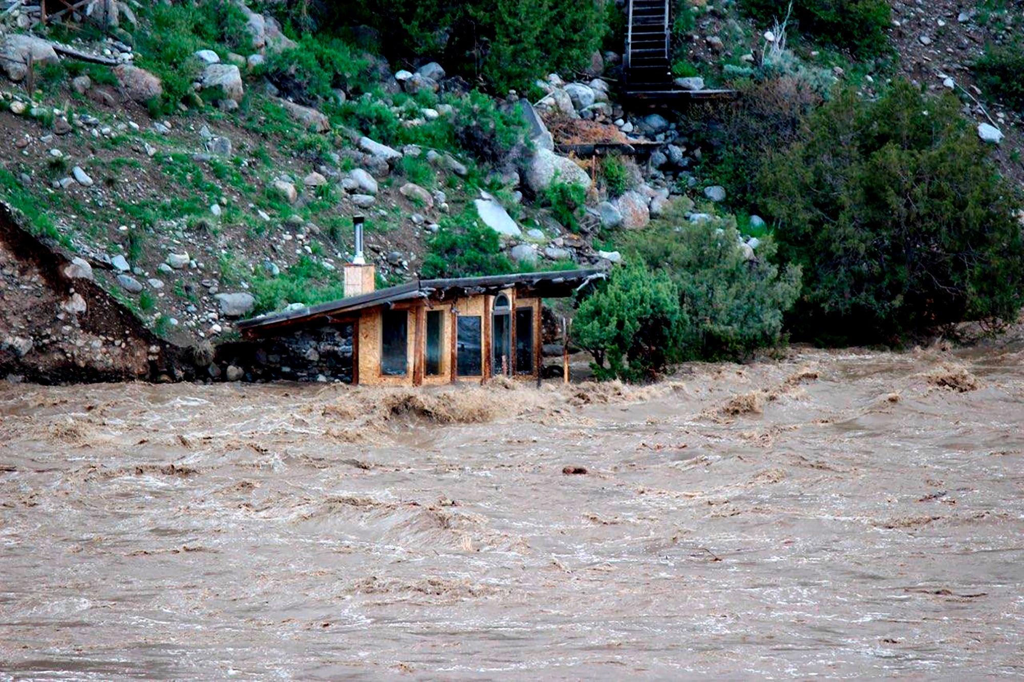 In this photo provided by Sam Glotzbach, the fast-rushing Yellowstone River flooded what appeared to be a small boathouse in Gardiner, Mont., on Monday, June 13, 2022, just north of Yellowstone National Park