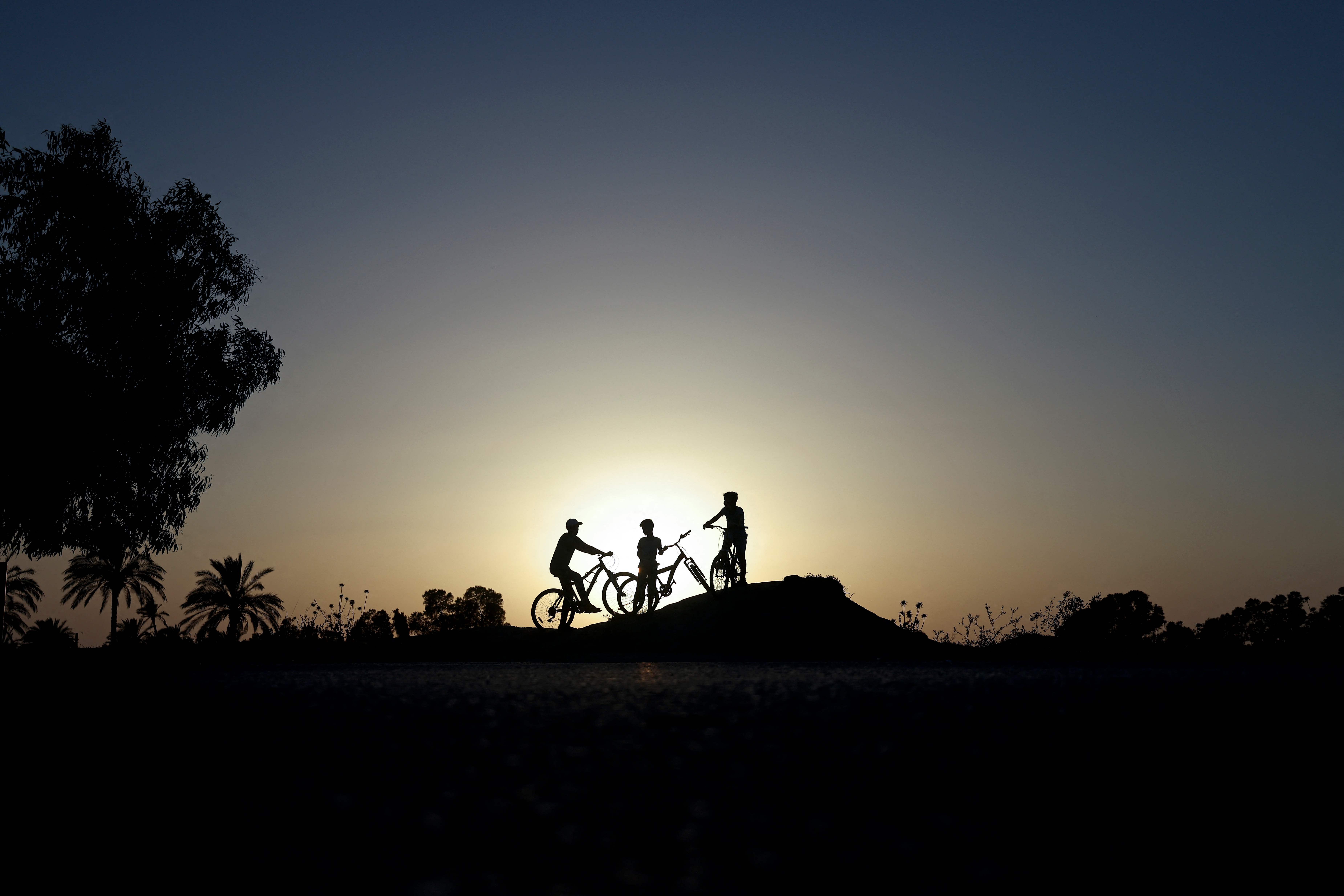 Palestinian children ride their bicycles at sunset in Gaza City