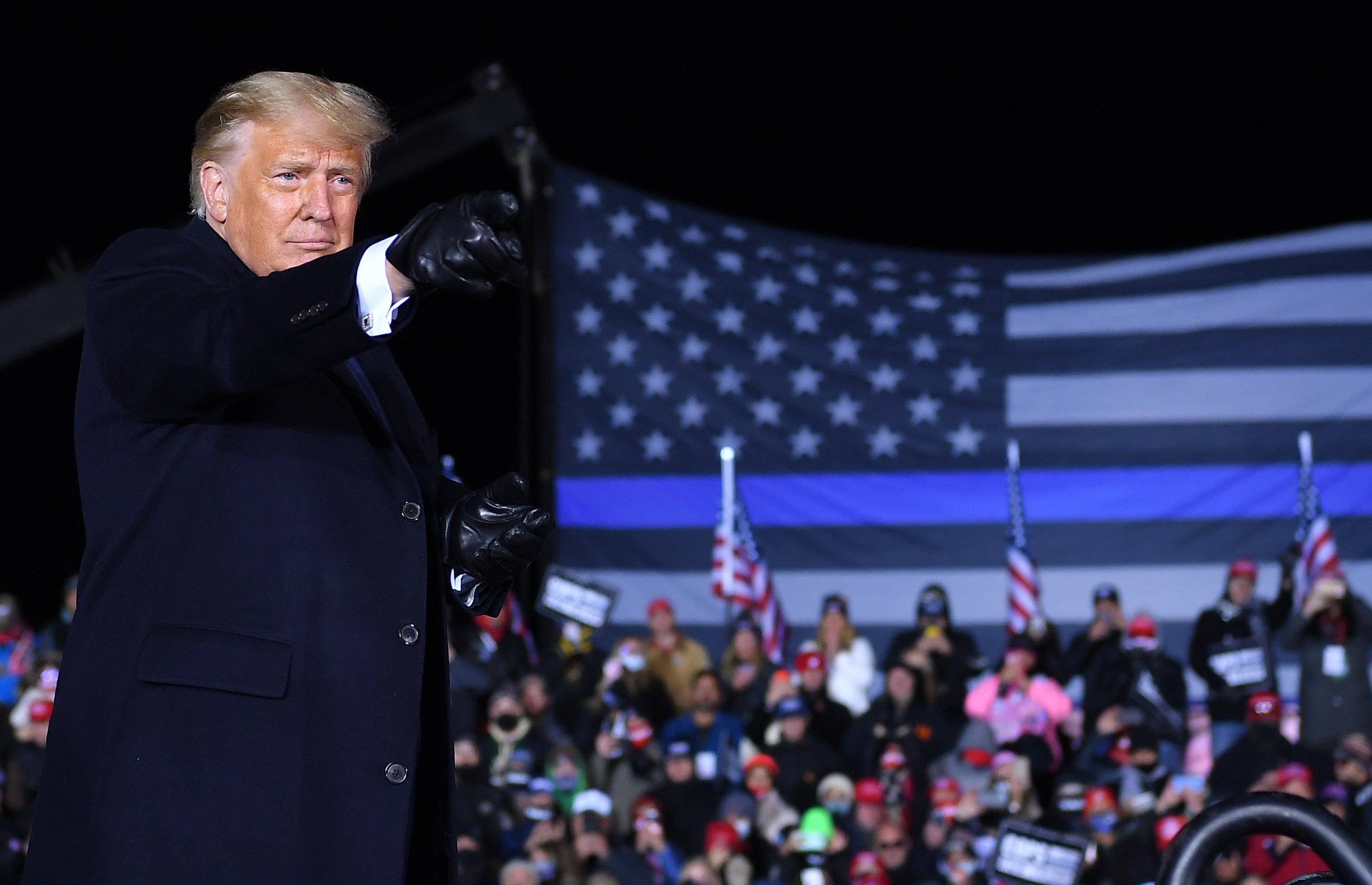 Donald Trump speaks in front of a thin blue line flag at a 2020 rally