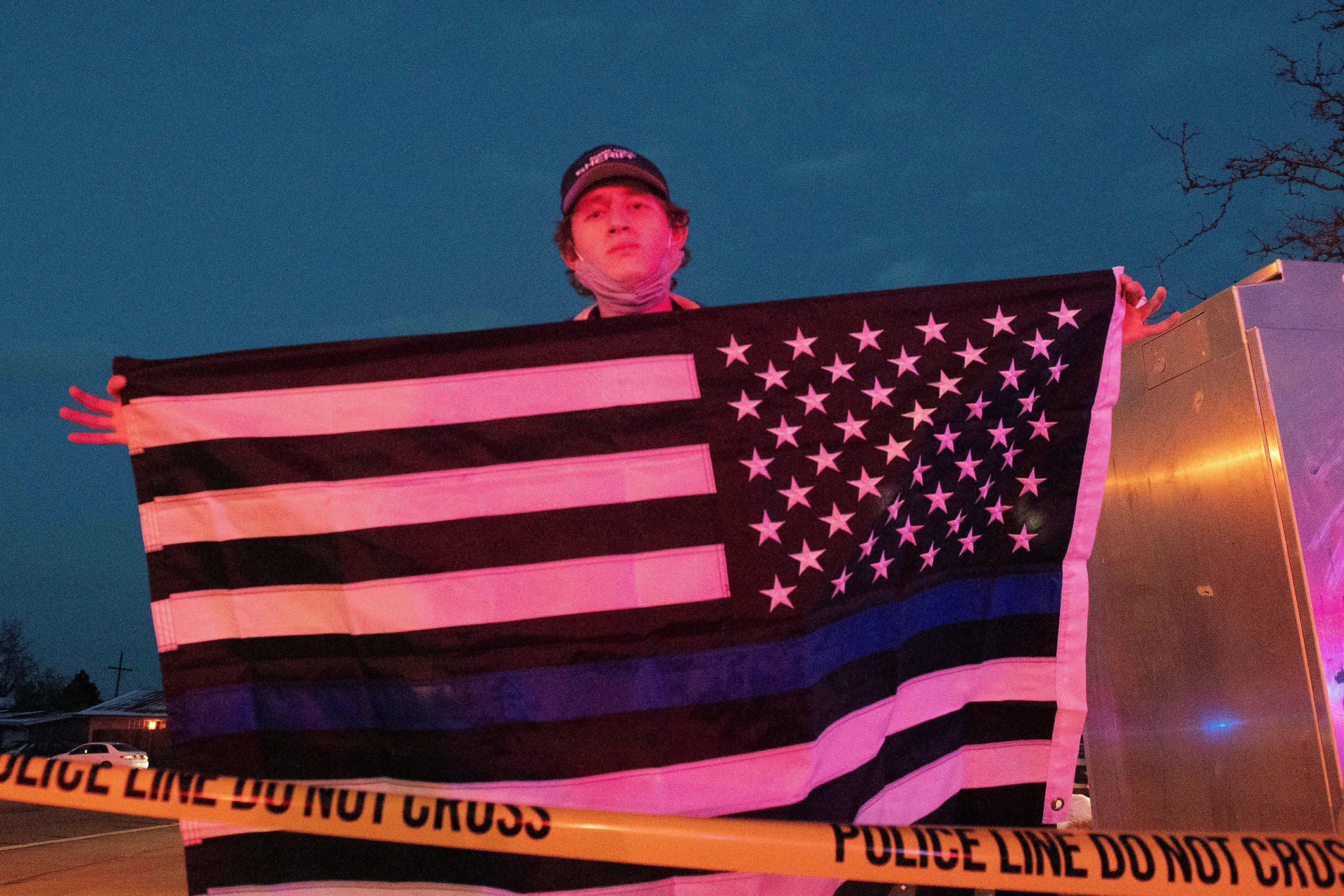 Zachary Smith holds a thin blue line flag in honor of Boulder Police officer Eric Talley who perished in the line of duty during an mass shooting at the King Soopers grocery store in Boulder, Colorado on March 22, 2021