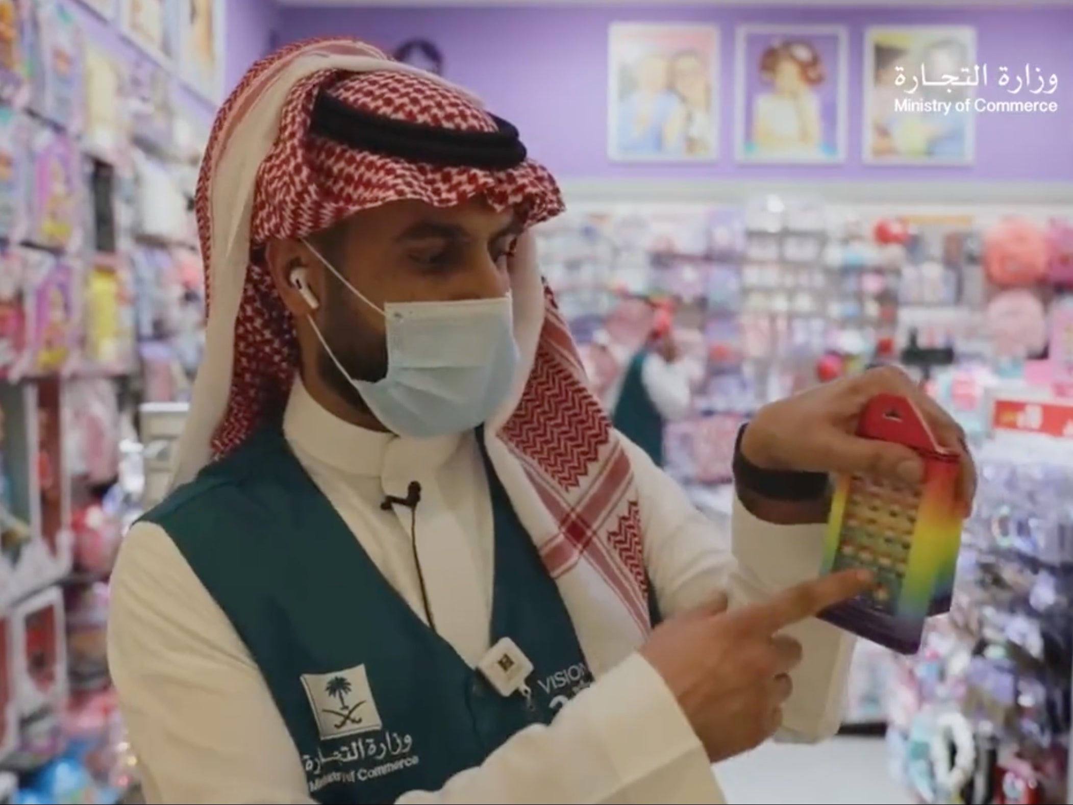 A Saudi official points out the rainbow colours on what appears to be a pack of false nails