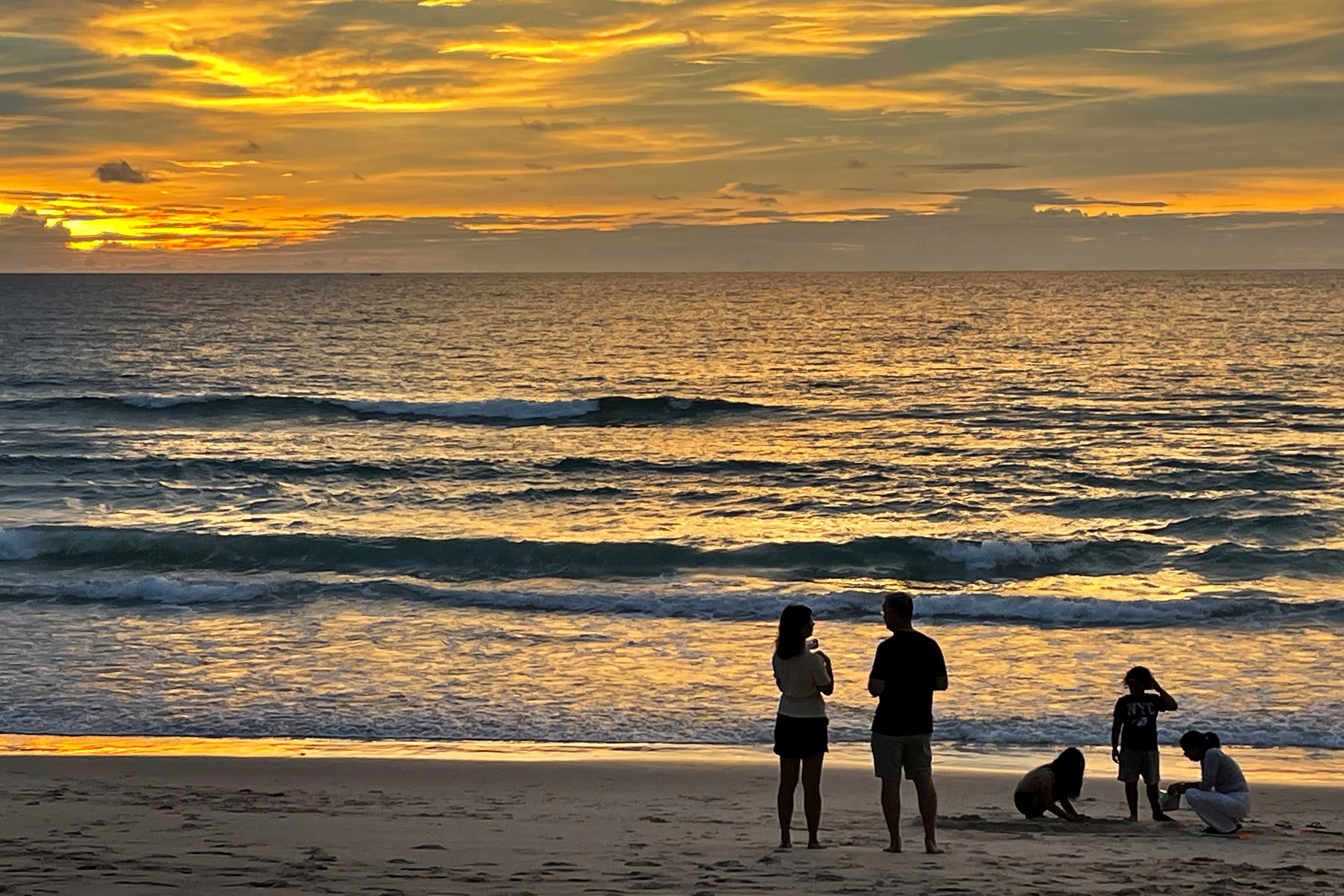 Tourists stand on Bang Tao Beach in Phuket, southern Thailand