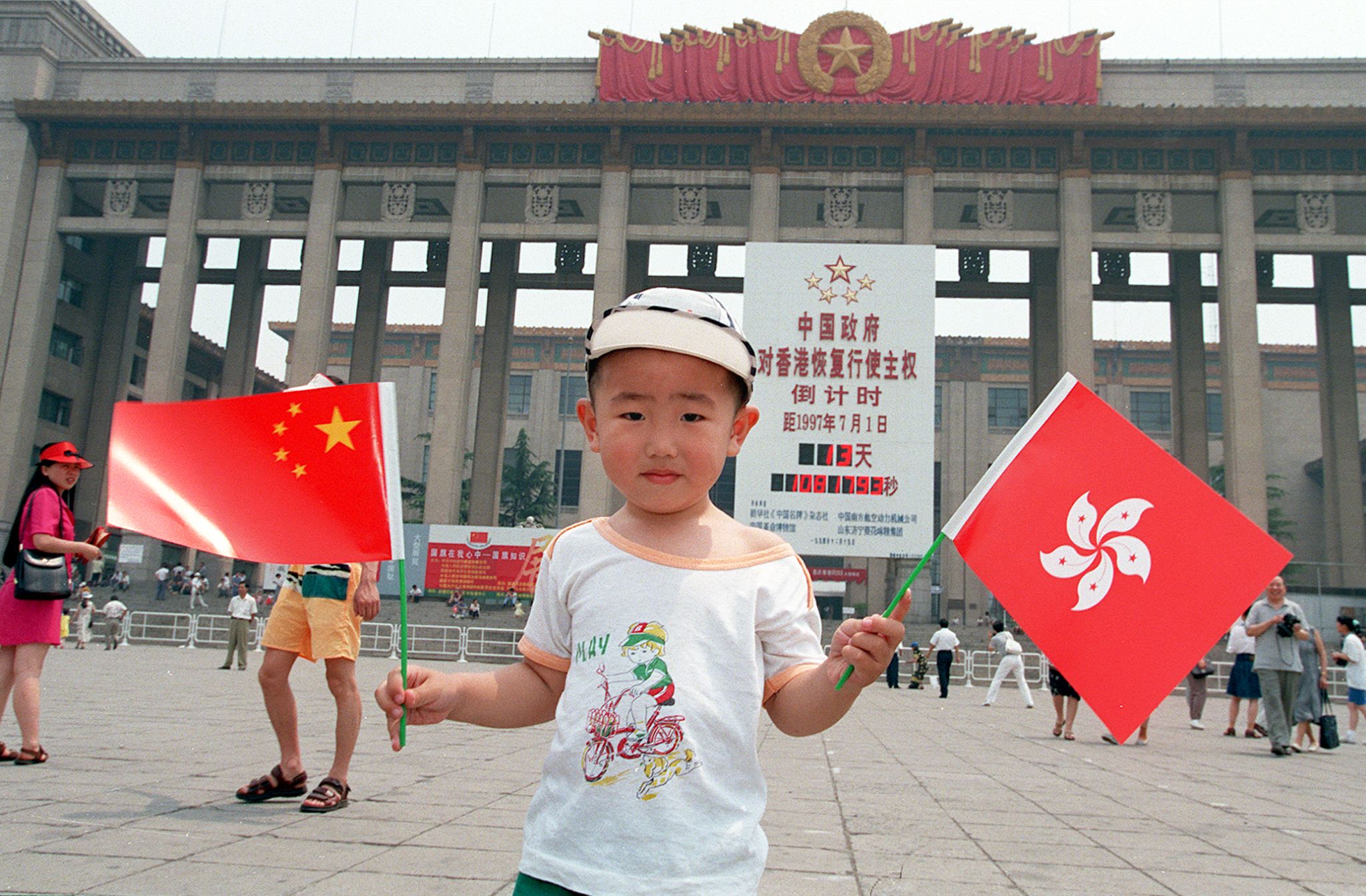 A small visitor shows off the Chinese (left) and Hong Kong (right) flags outside the Chinese History Museum in Tiananmen Square