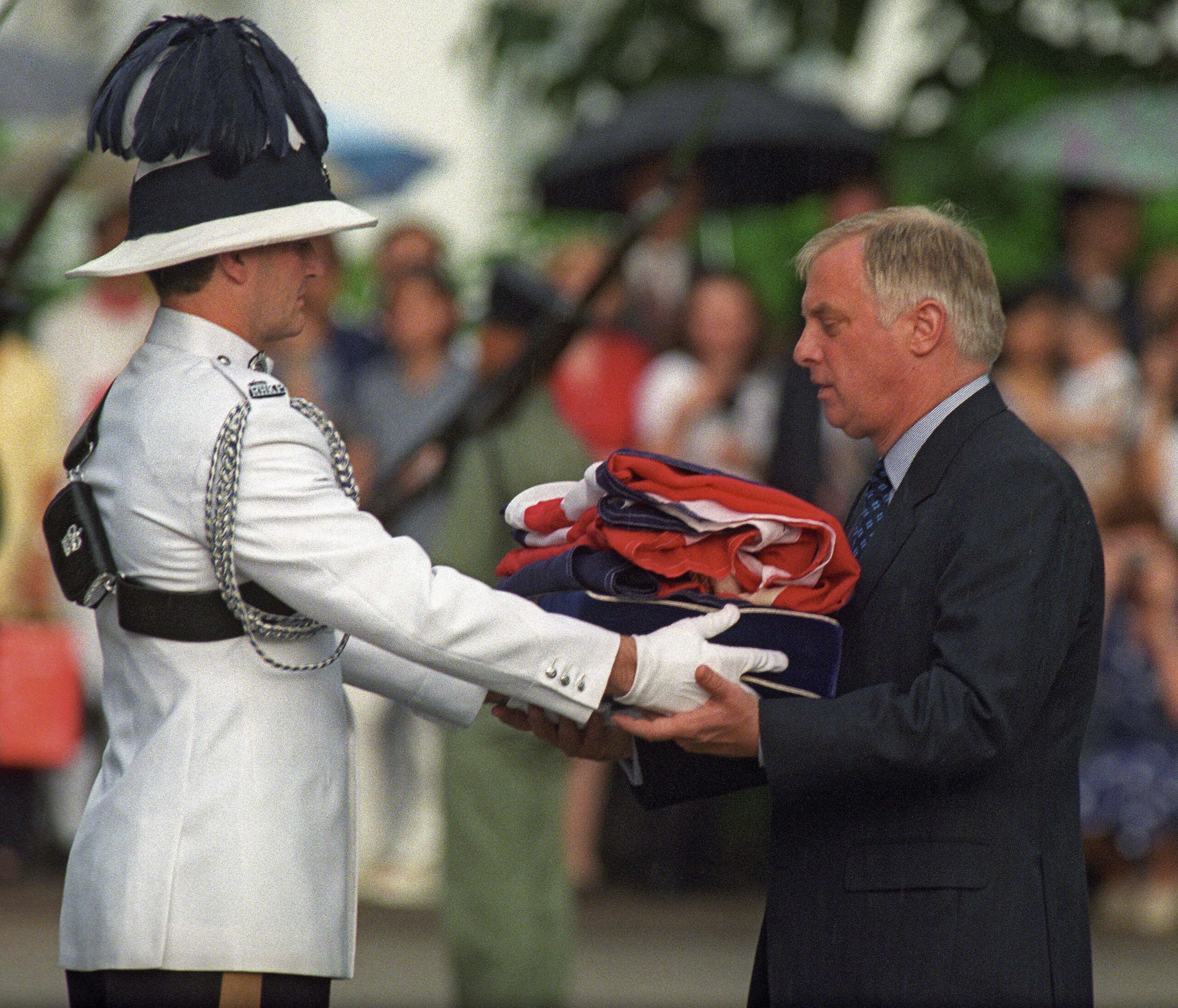 Chris Patten (right) receives the union jack flag after it is lowered for the last time at the governor’s official residence