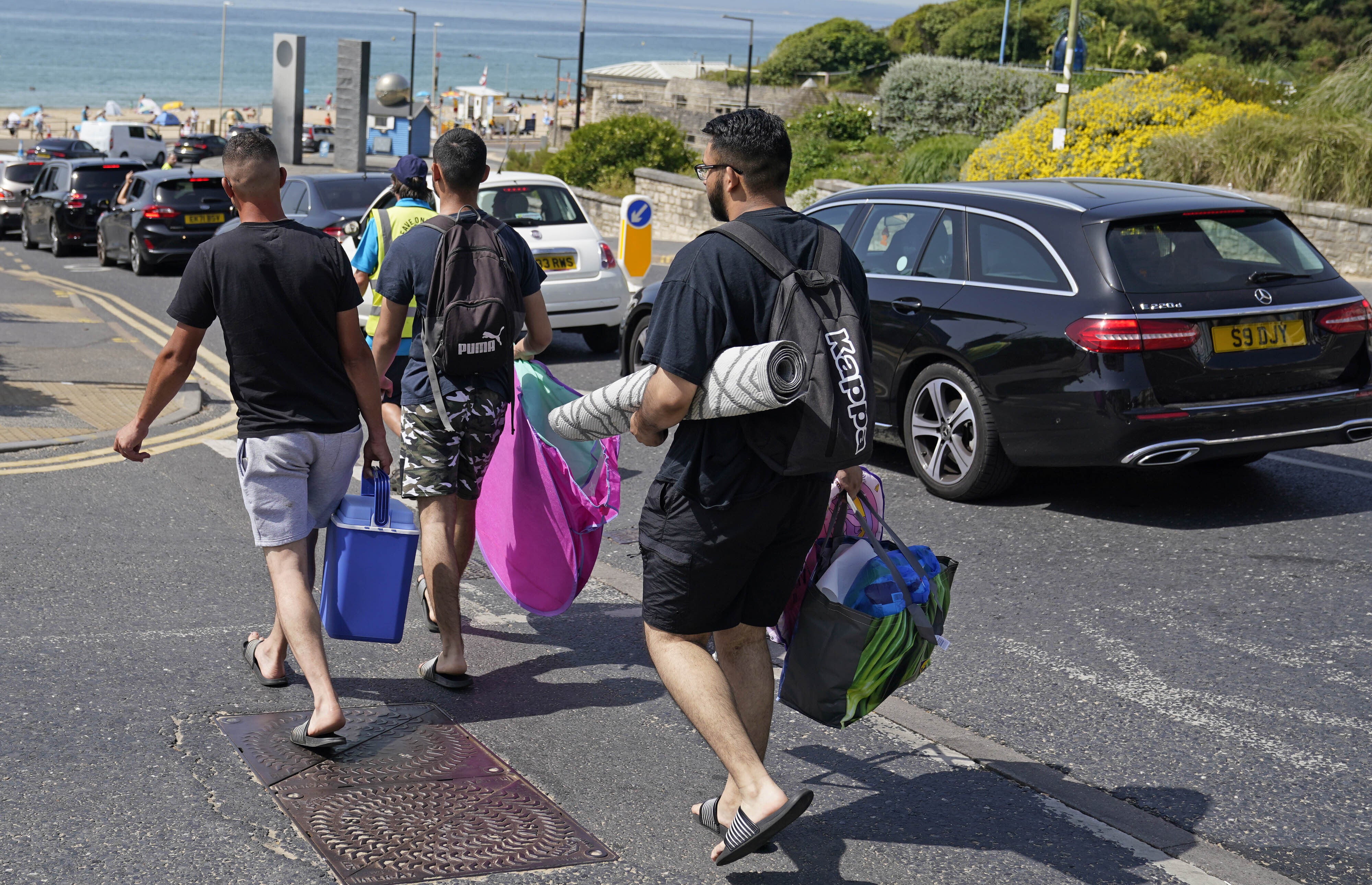 People walk to Boscombe beach this morning with mats and coolers