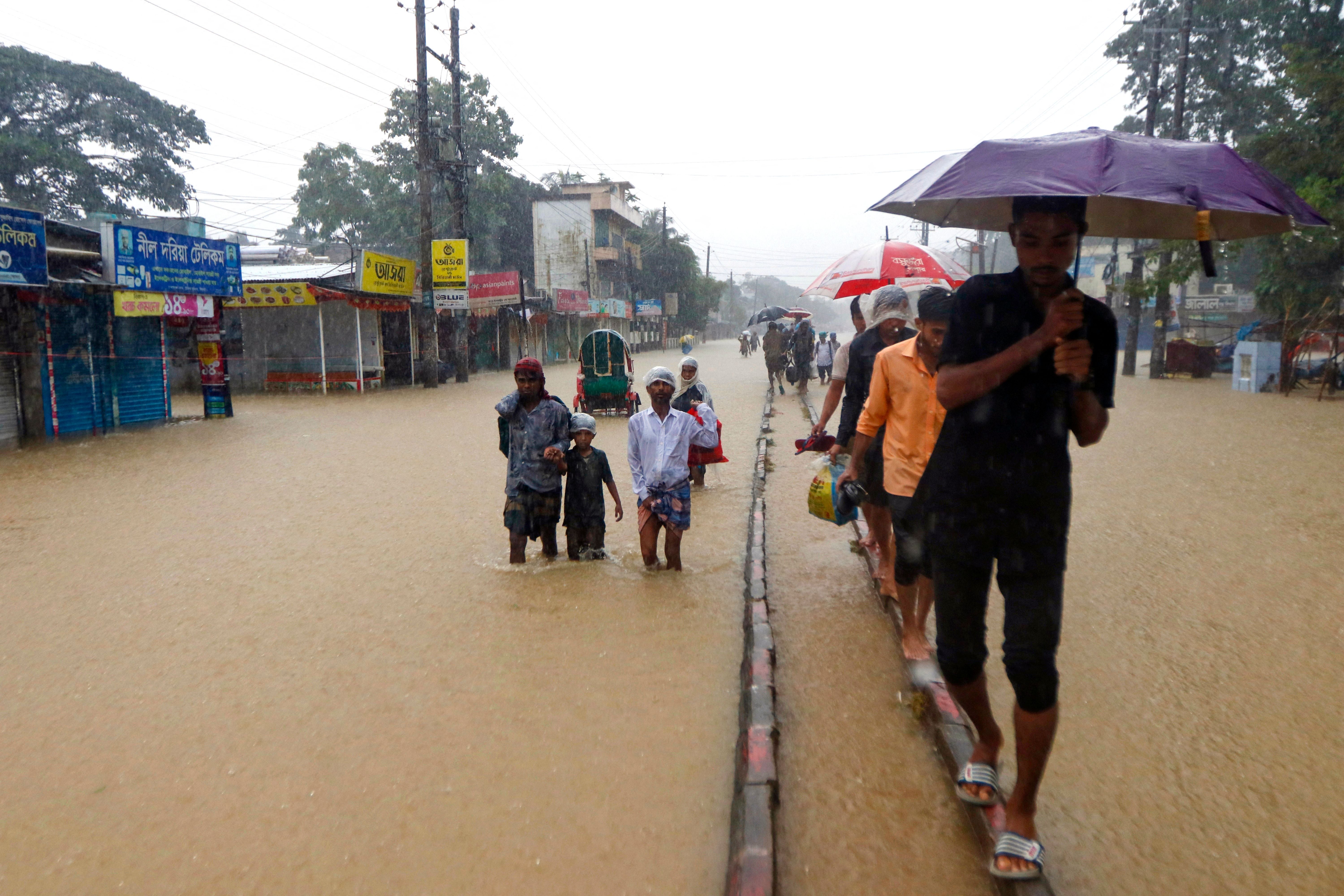 People wade along a flooded road following heavy monsoon rainfall in Sylhet in 2022