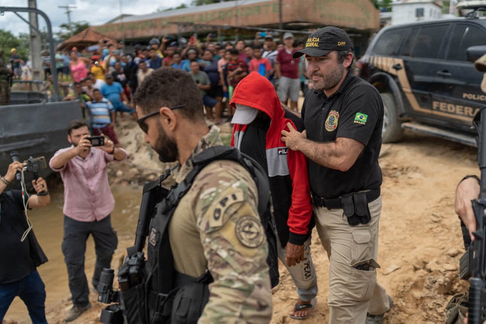 Federal police officers escort suspect Amarildo da Costa de Oliveira, alias "Pelado", to board a boat to the site where a rescue mission isn taking place in Atalaia do Nort