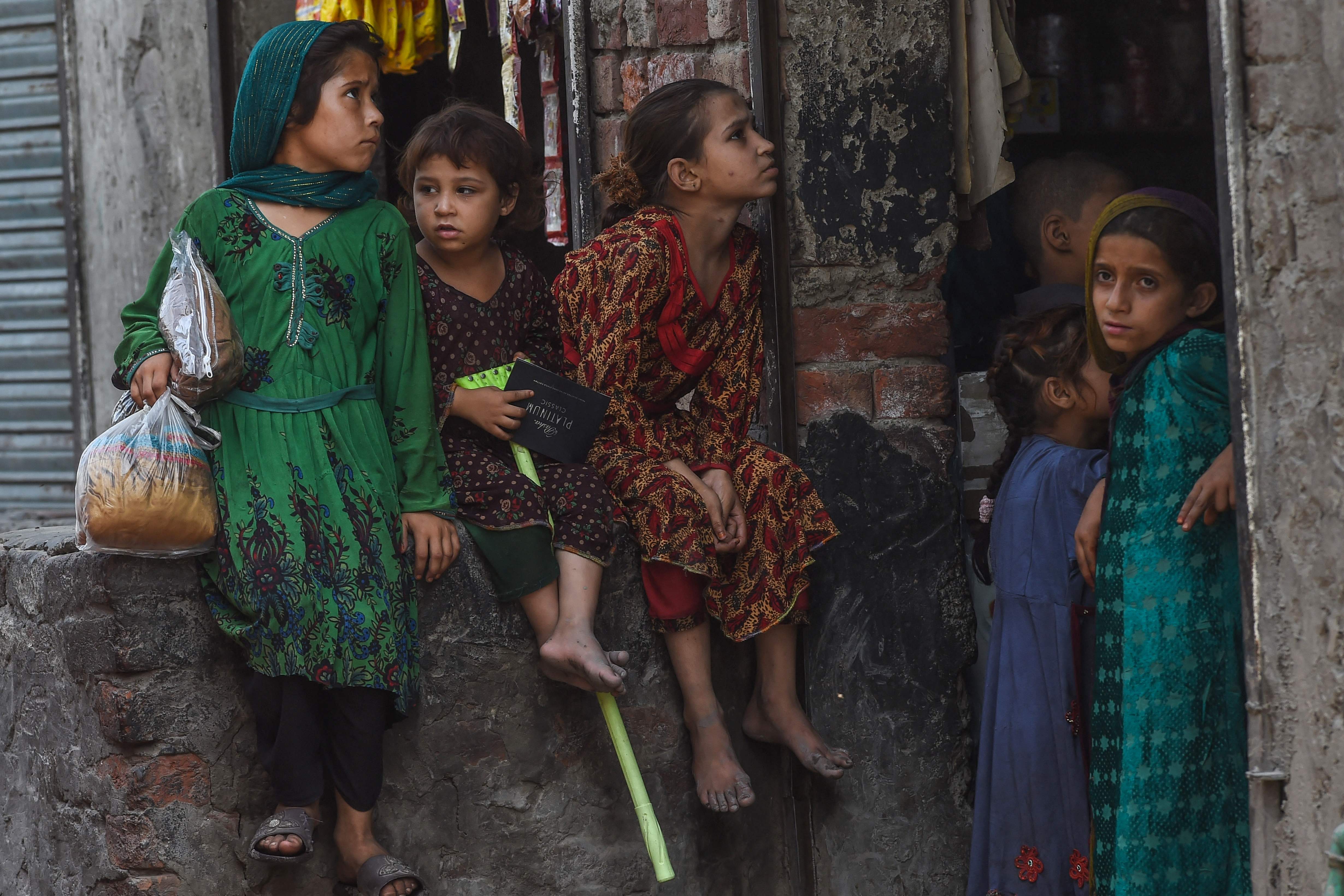 Children belonging to Afghan refugees living in Pakistan sit outside a shop on the outskirts of Lahore