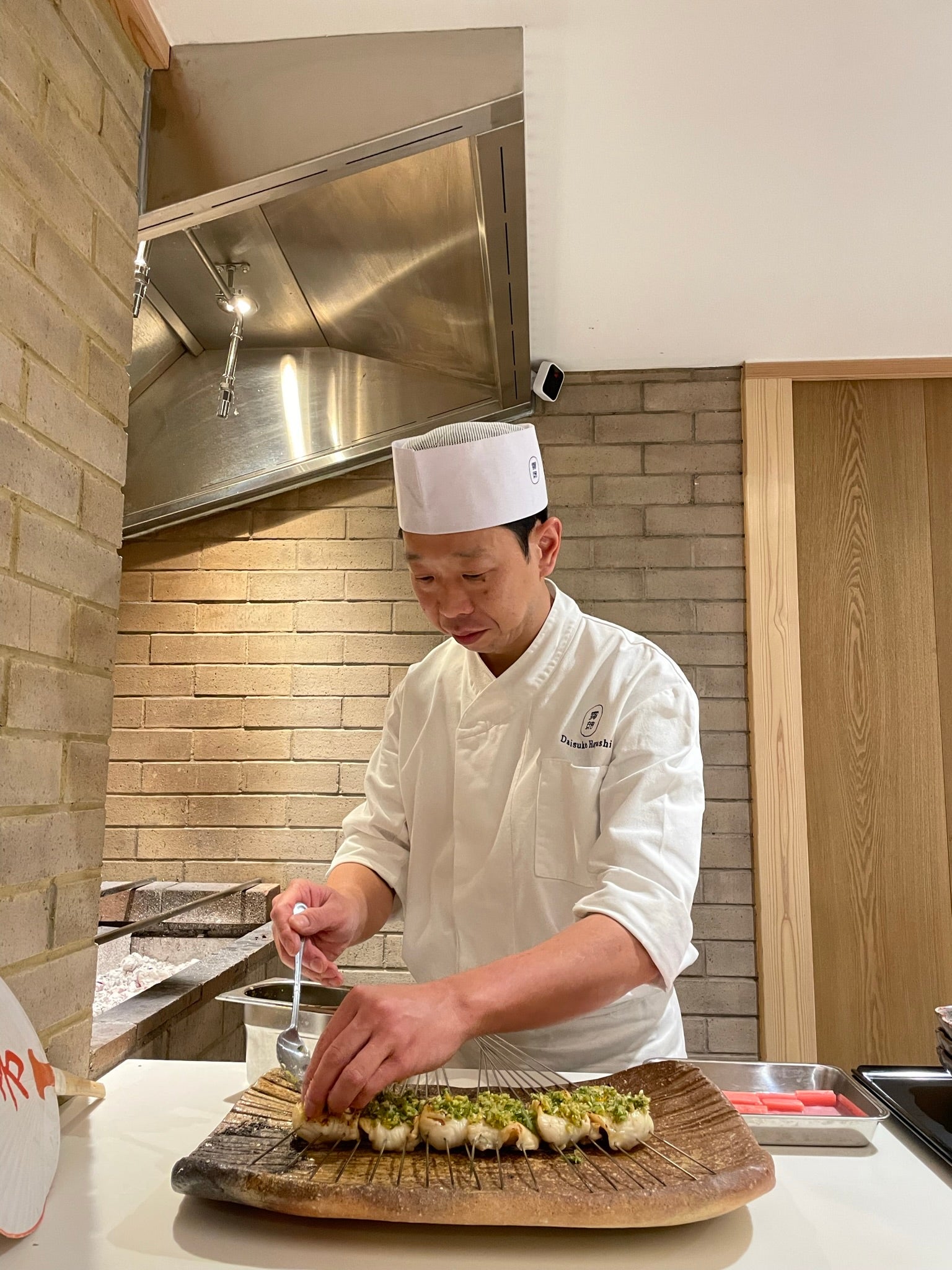 Hayashi prepares Cornish brill that has been grilled over the fire behind him