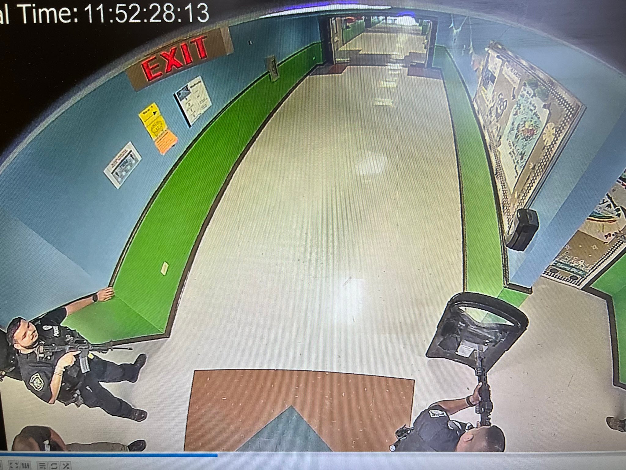 Police officers stand outside a classroom at Robb Elementary School in Uvalde, Texas, on 24 May, 2022, armed with rifles and a ballistic shield.