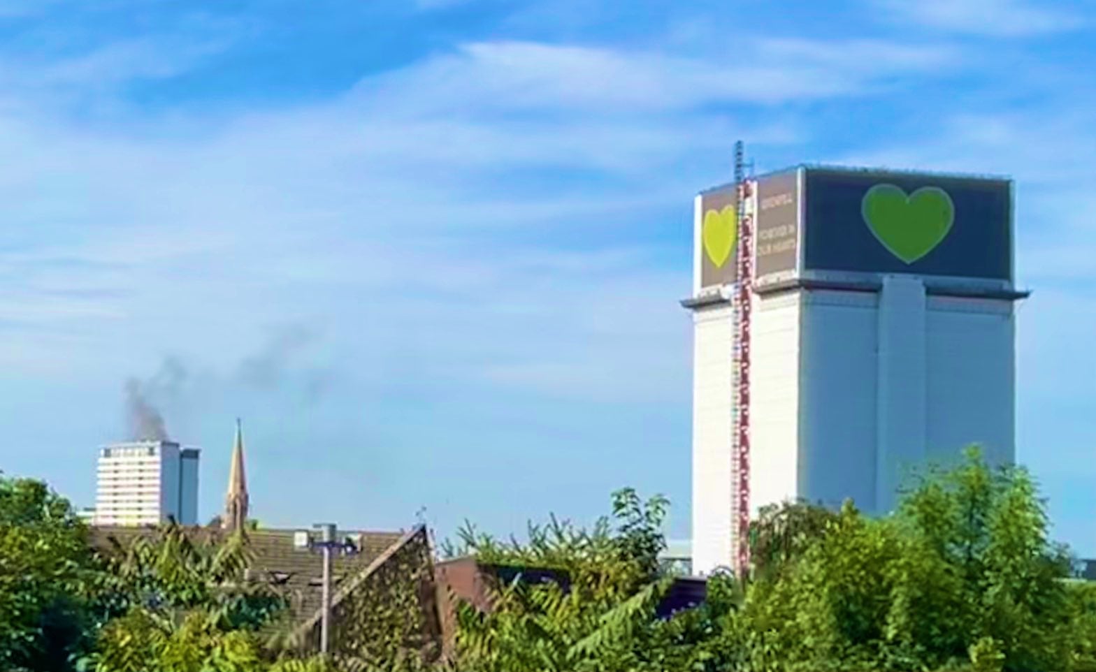 Grenfell Tower is pictured with the Shepherd’s Bush fire in the distance