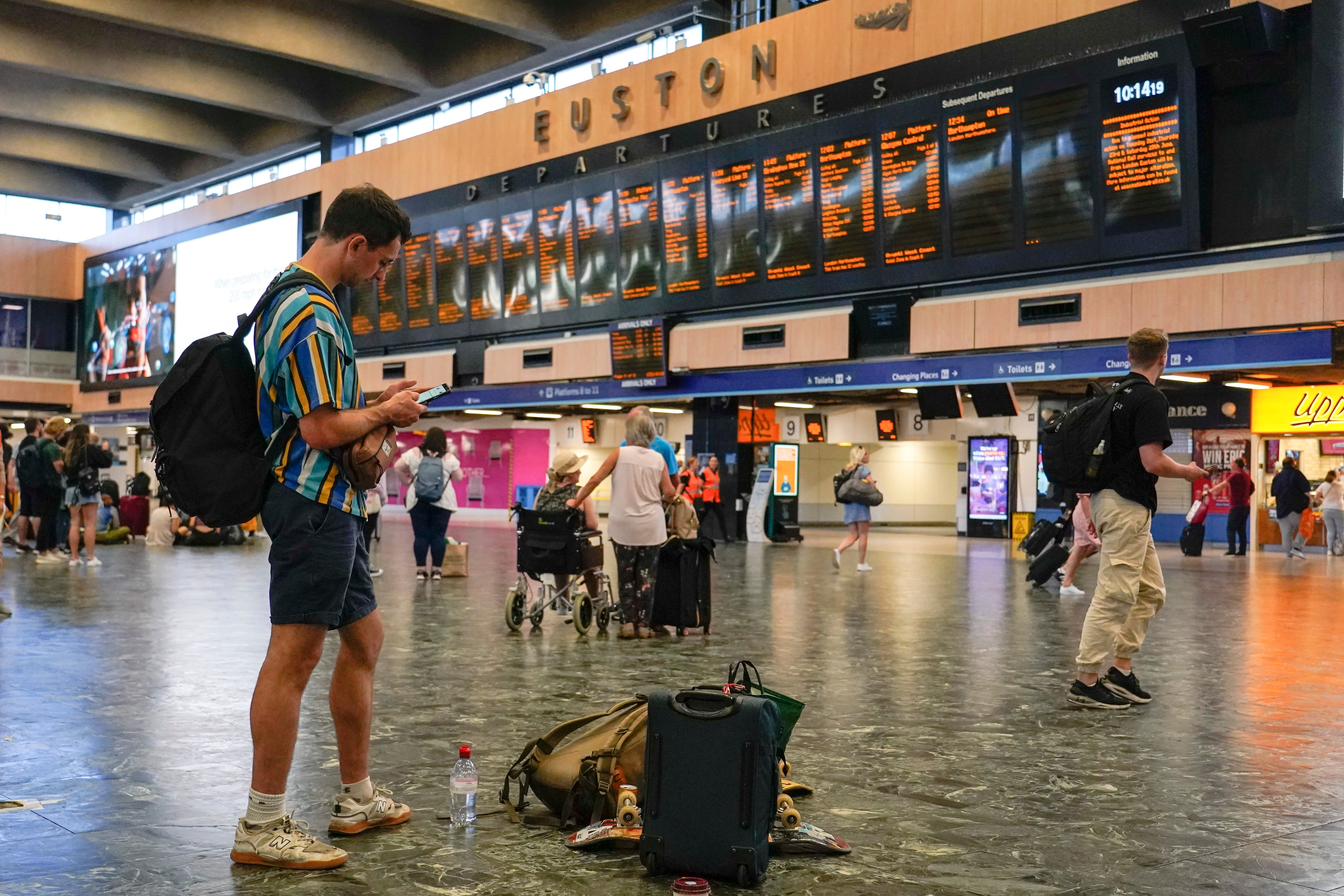 Passengers await their trains to be announced at a quiet Euston Station