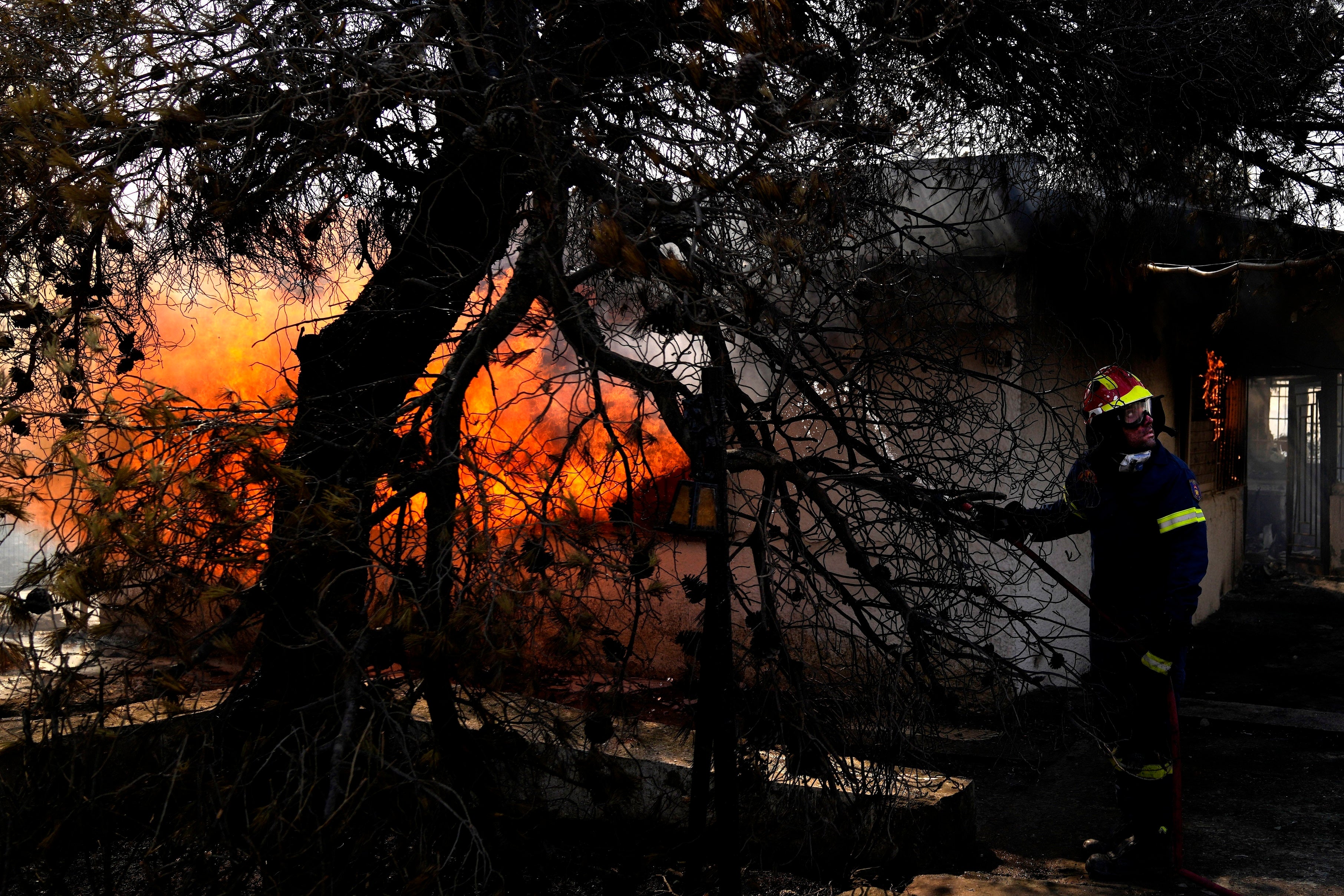 A firefighter tries to extinguish the fire in a house during a wildfire in Thea area, northwest of Athens, Greece, in August last year