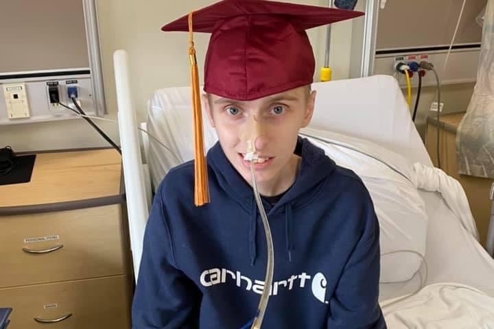 Eric poses in hospital with a graduation cap. He graduated high school early and later perused his goal of becoming a heavy duty mechanic by starting his level 1 apprenticeship in college