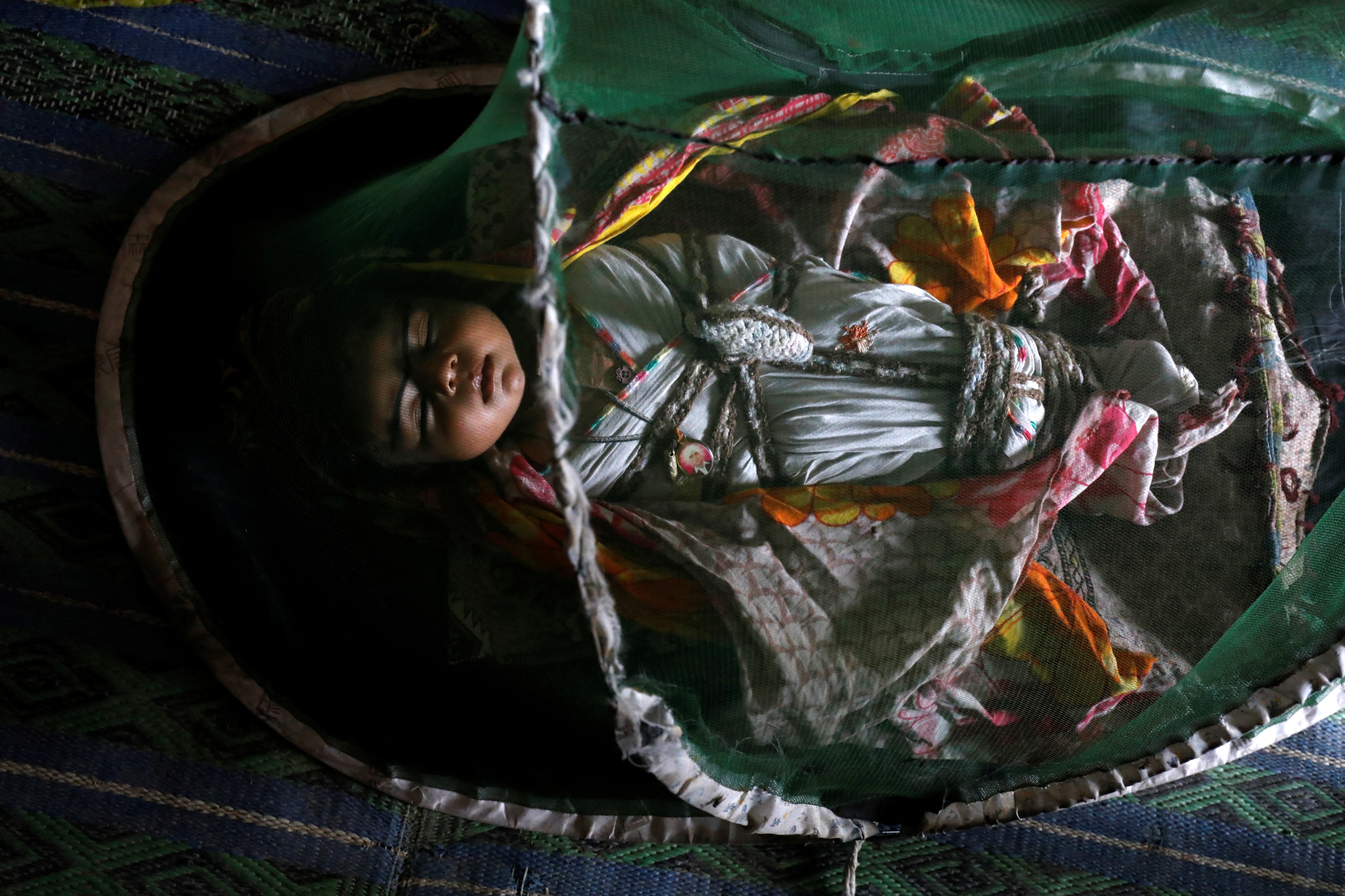 One-month-old Vamar Kumar sleeps at home under a mosquito net