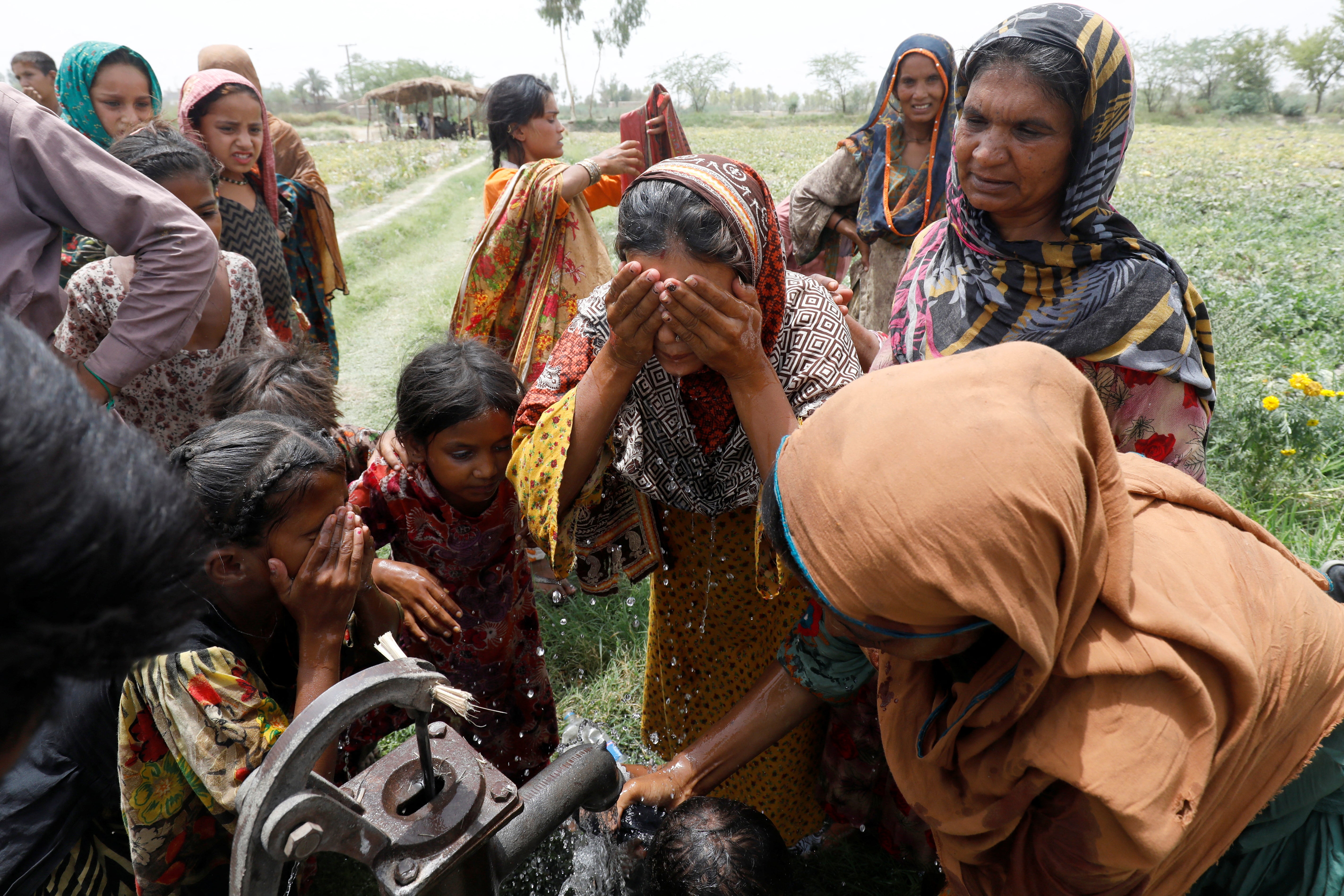 Women and children wash themselves after work at a muskmelon farm