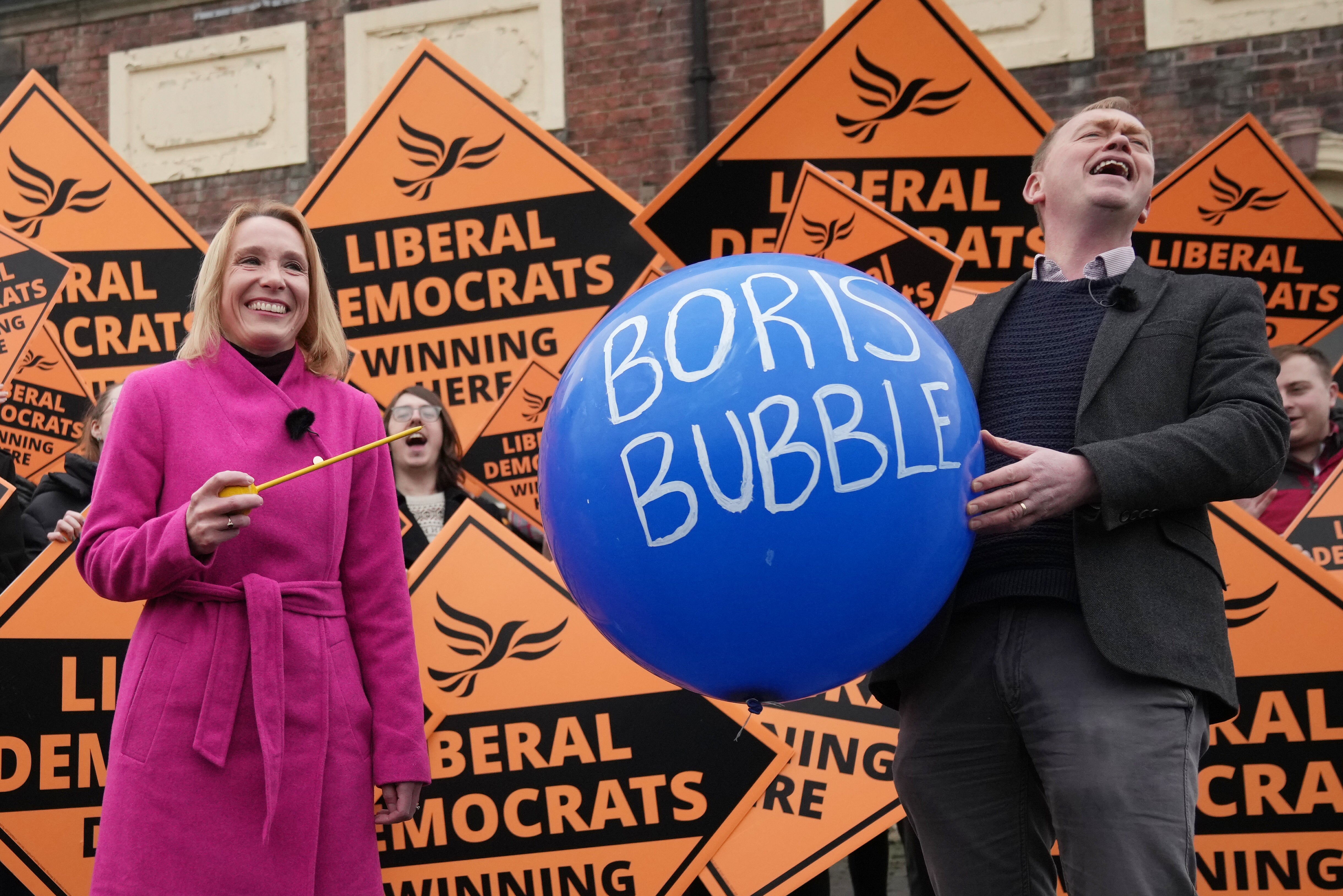 MP Helen Morgan celebrated by using a long yellow pin to burst a large blue balloon