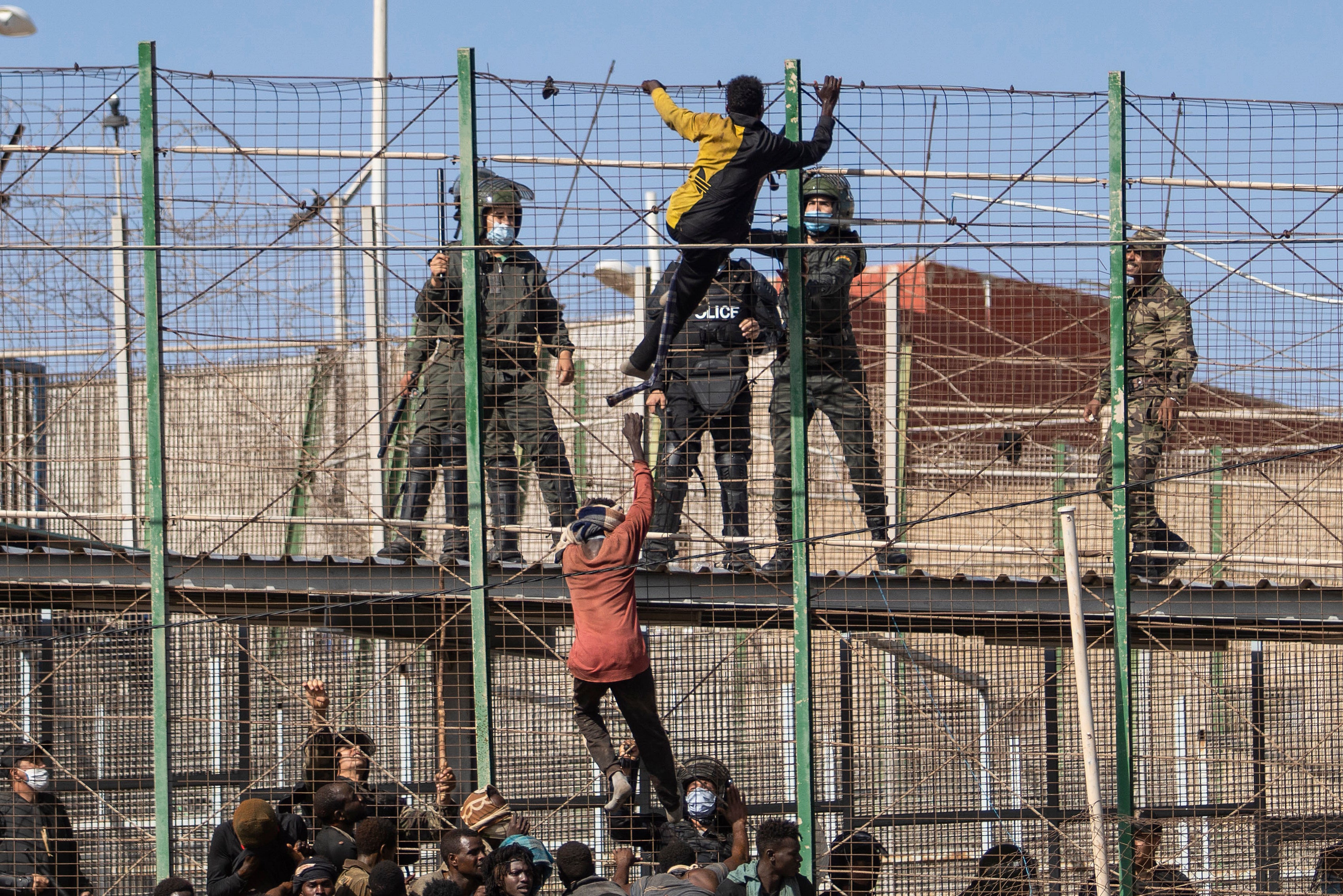 People climb the fences separating the Spanish enclave of Melilla from Morocco on Friday