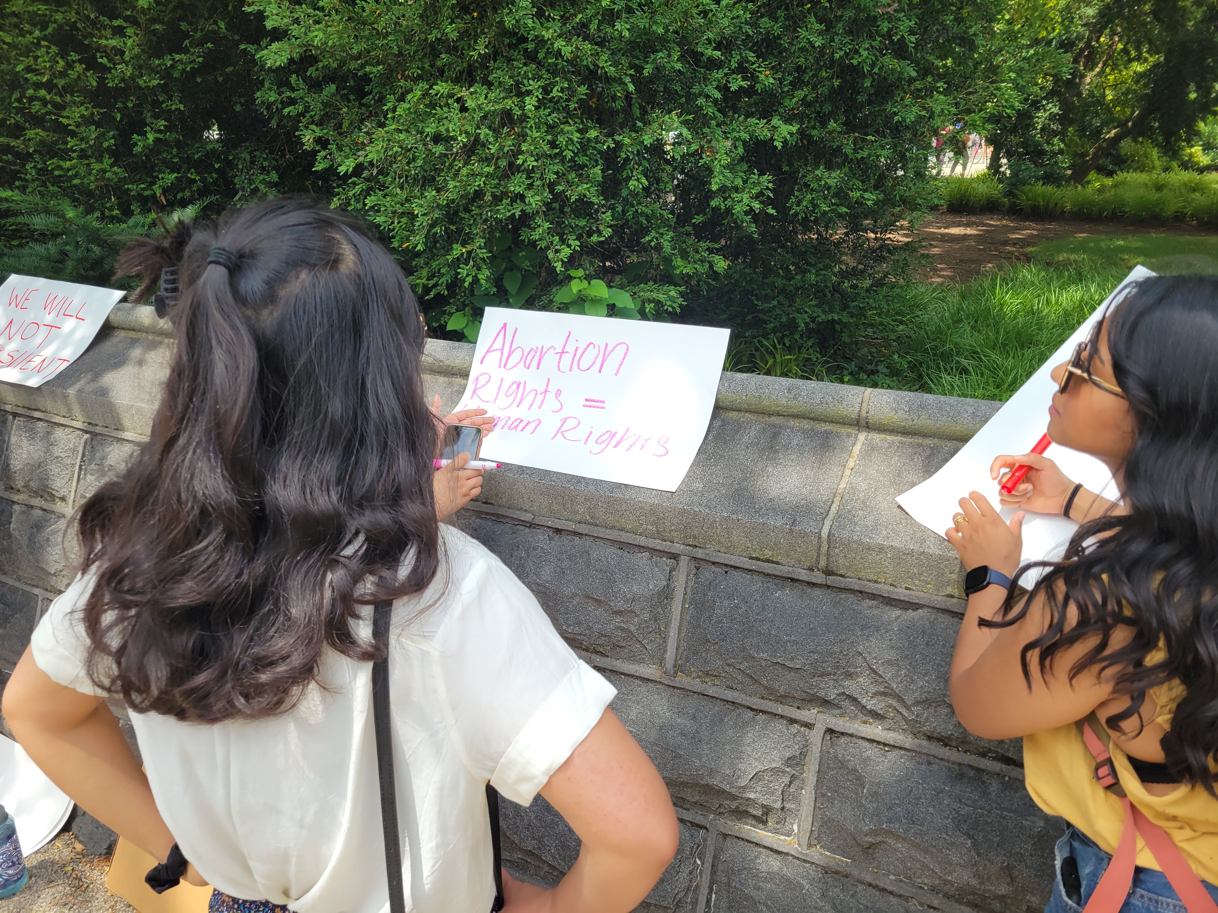 Demonstrators make picket signs on-site as the crowd grows outside the Supreme Court on Thursday