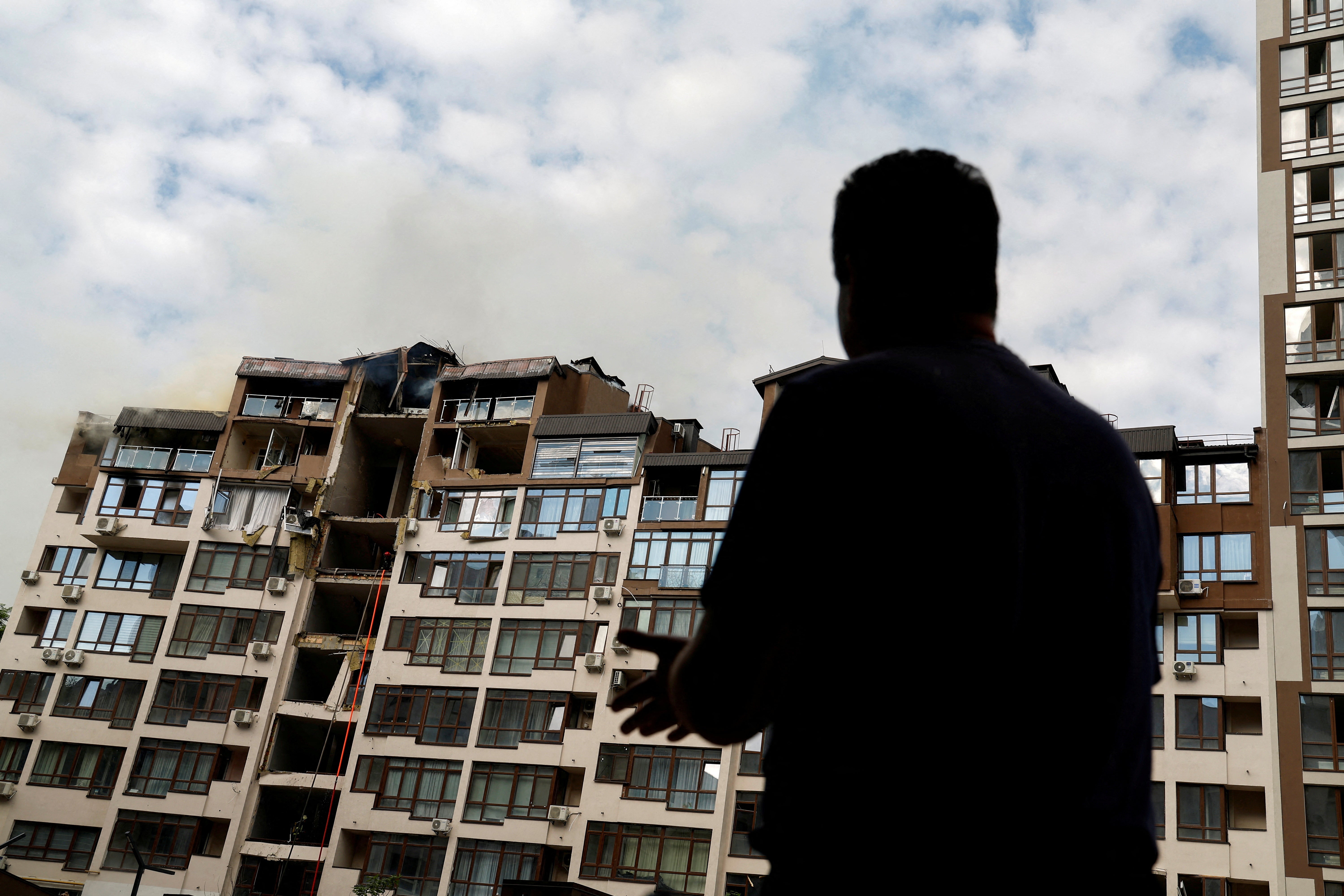 A man looks at the wreckage of a residential building damaged by a Russian missile strike