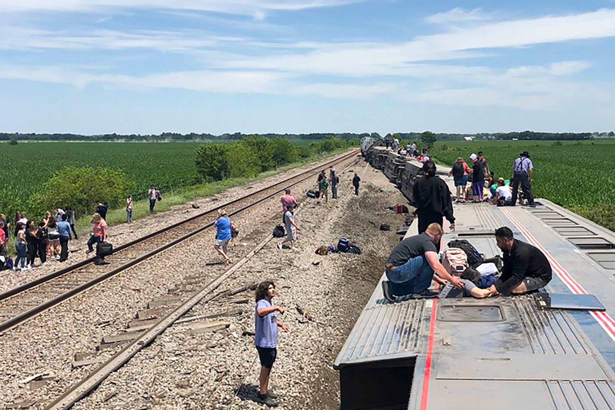 In this photo provided by Dax McDonald, an Amtrak passenger train lies on its side after derailing near Mendon, Missouri, on Monday