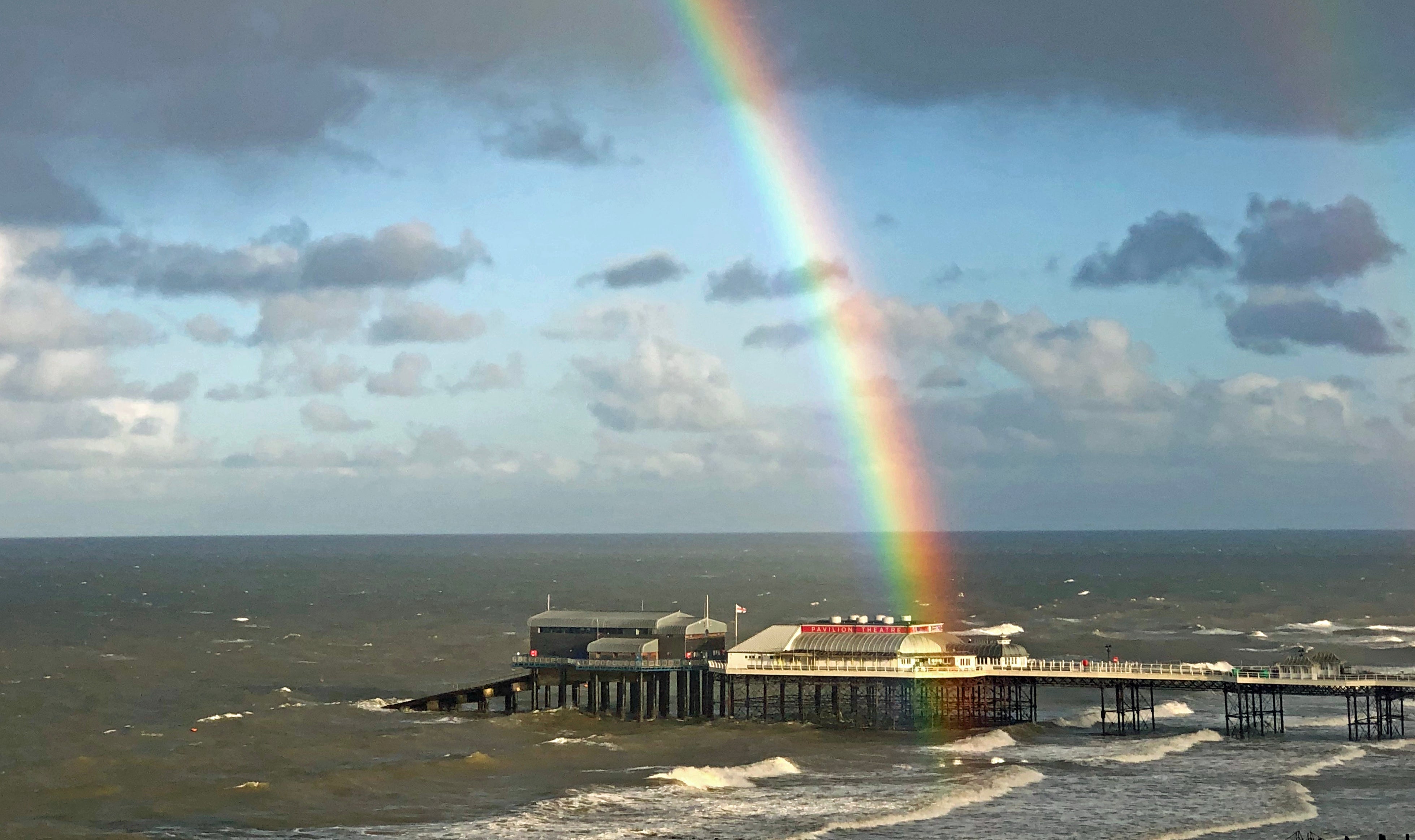 A rainbow is seen hanging over the pier in Cromer, Norfolk (Laura Kerr/PA)