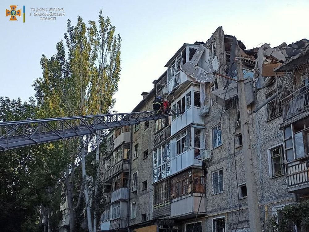 A rescuer helps a man to be evacuated from a residential building hit by a Russian military strike