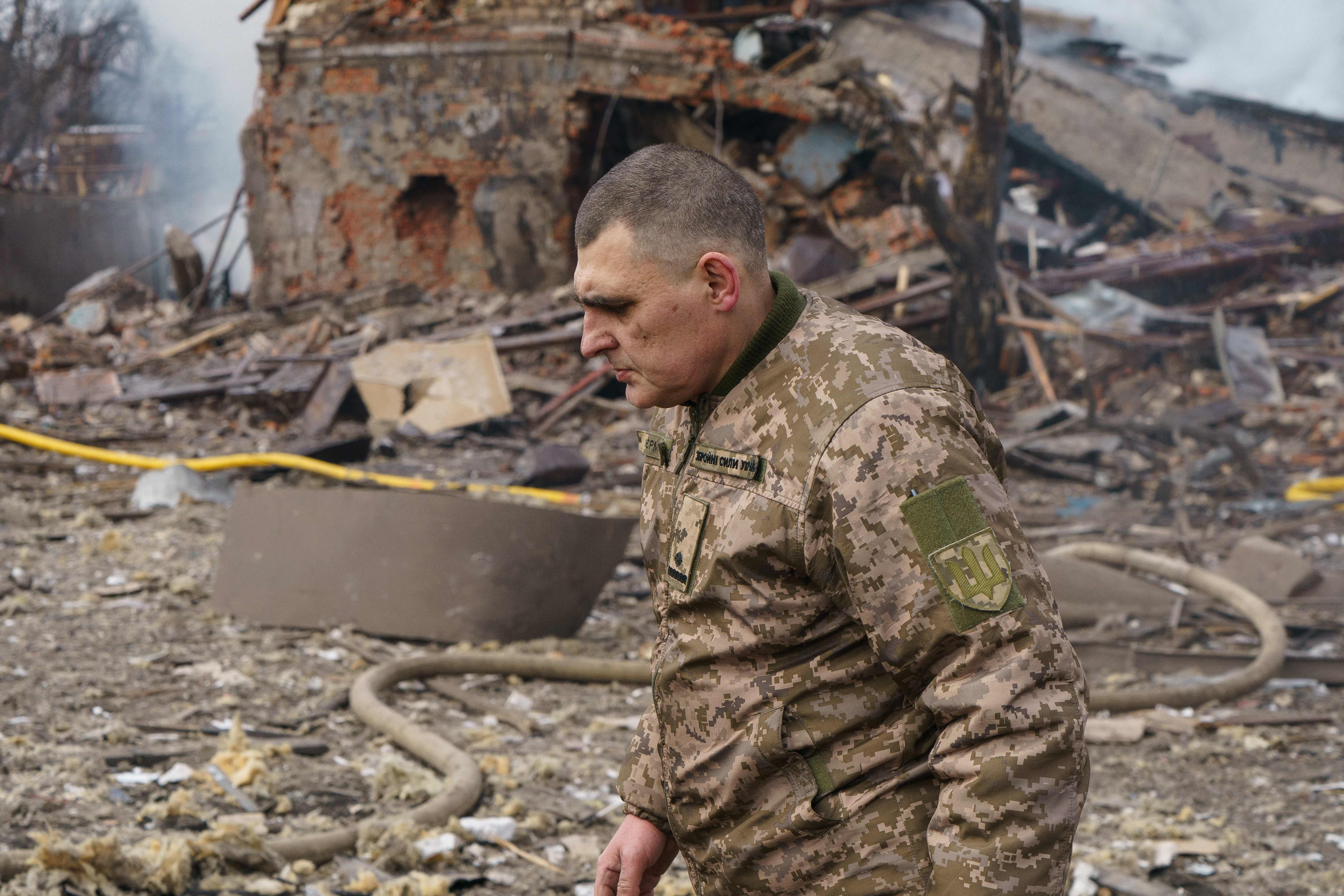 Ukraine army public affairs officer Valentin Yermolenko walks in front of a destroyed shoe factory following an airstrike in Dnipro