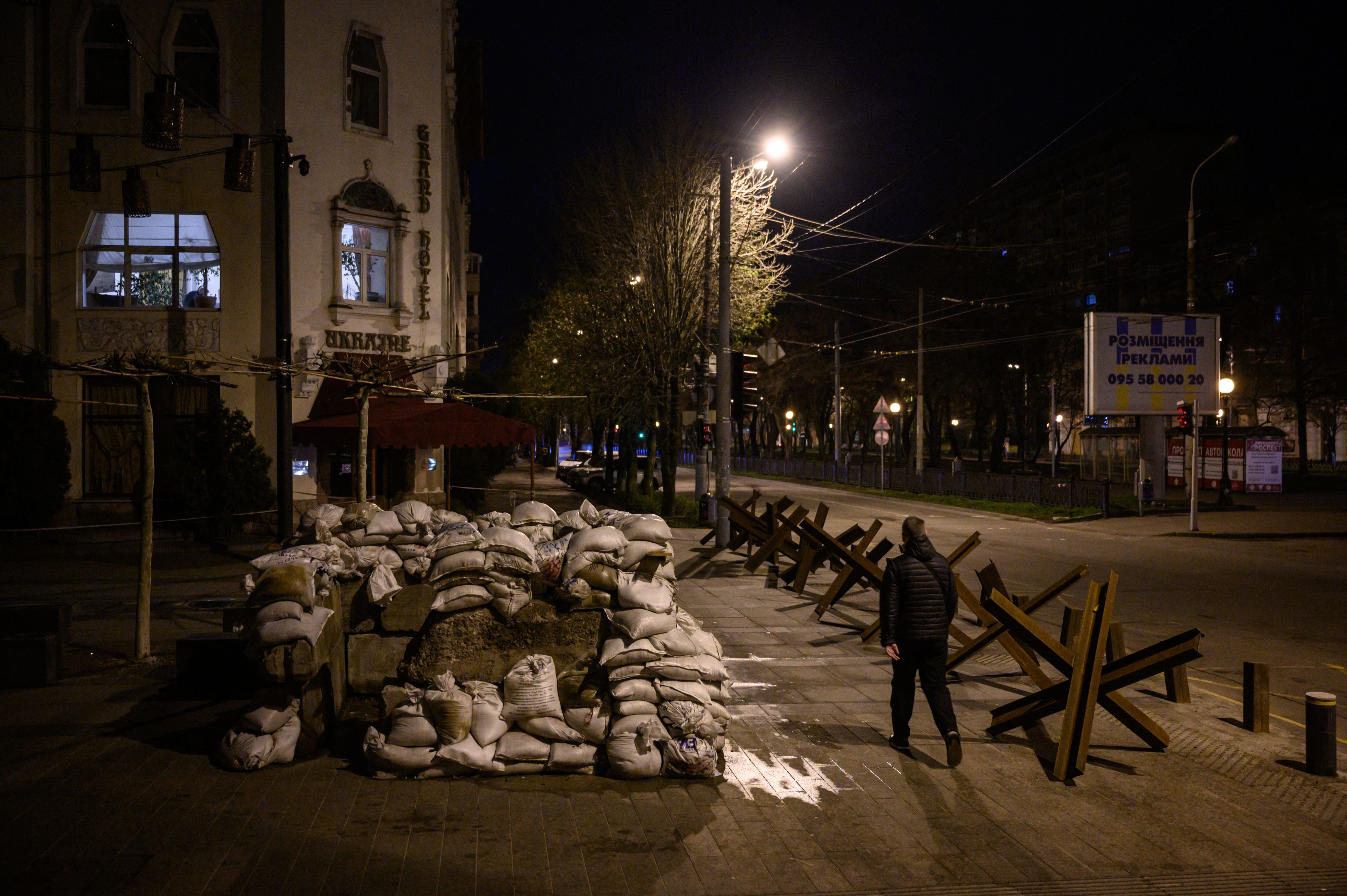 A pedestrian walks along a street past anti-tank obstacles shortly before a curfew in Dnipro